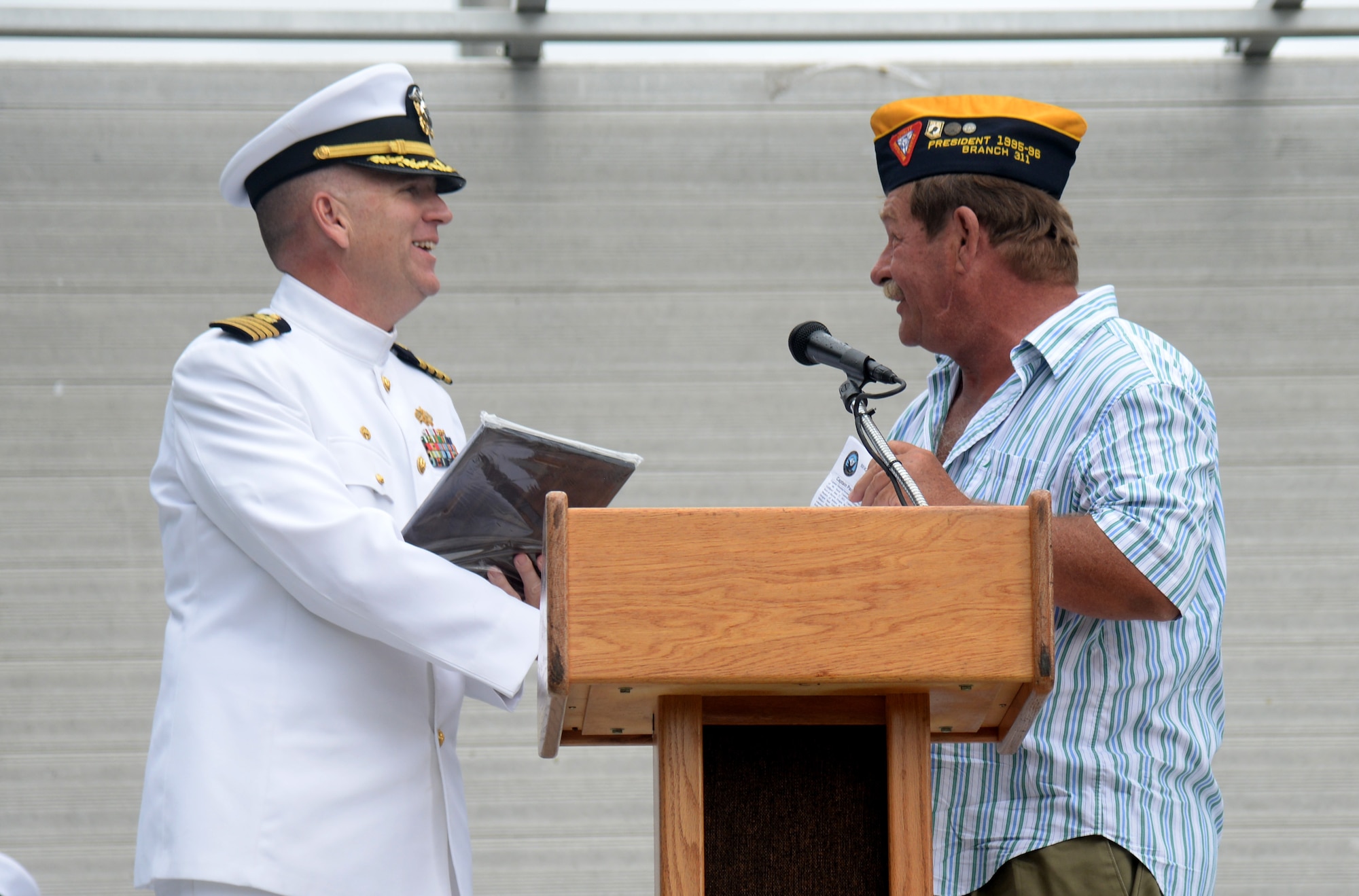 Navy Captain Paul Odenthal, Naval Construction Battalion Center commanding officer, receives a gift from a local veteran at the 2015 Biloxi National Cemetery Memorial Day ceremony, May 25, 2015, Biloxi, Miss. Local veterans, family members and Keesler Air Force Base and Naval Construction Battalion Center leadership attended to honor and remember the lives of fallen U.S. military heroes. (U.S. Air Force photo by Senior Airman Holly Mansfield)