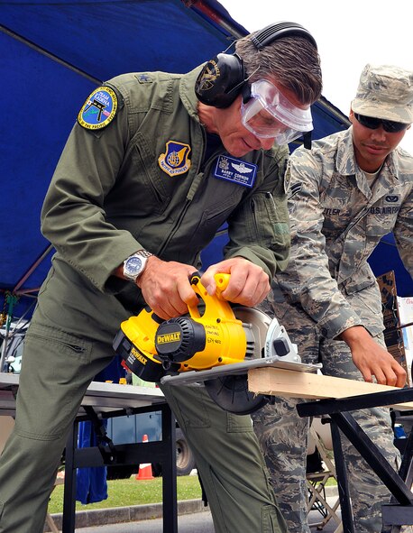 U.S. Air Force Brig. Gen. Barry Cornish, 18th Wing commander, demonstrates proper wood cutting safety during the Wingman Safety Day at the Risner Fitness Center on Kadena Air Base, Japan, May 21, 2015. The Wingman Day emphasizes safe practices and the importance of being a good wingman by caring for fellow Airmen during their time of need. (U.S. Air Force photo by Naoto Anazawa)