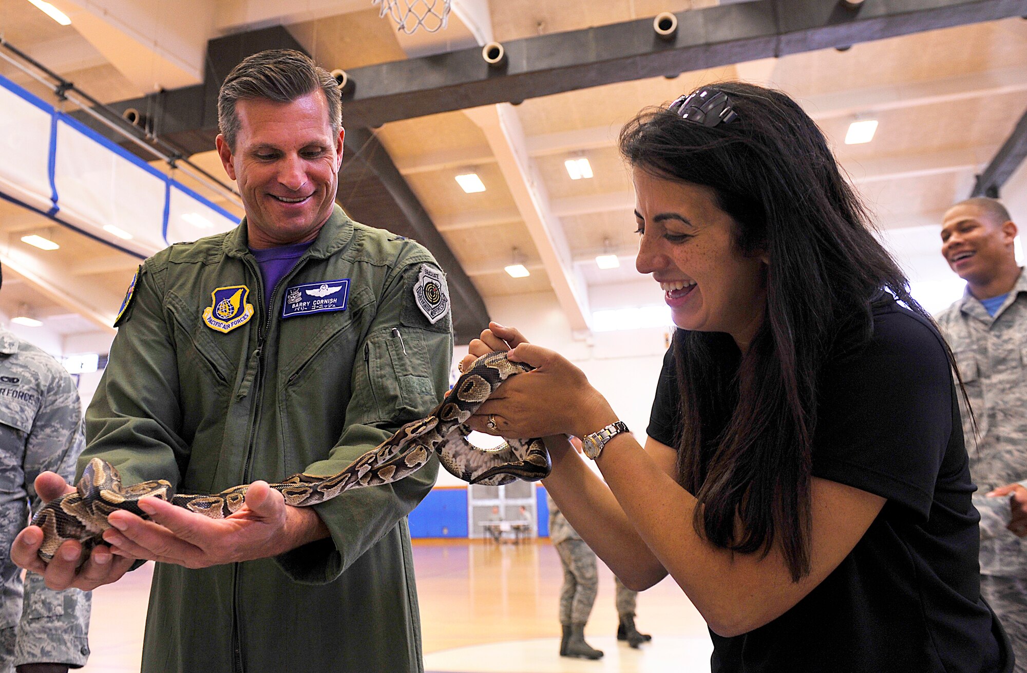 U.S. Air Force Brig. Gen. Barry Cornish, 18th Wing commander, and Lisa Velez, 18th Wing community support coordinator, carry snakes during the second annual Wingman Safety Day at the Risner Fitness Center on Kadena Air Base, Japan, May 21, 2015. The Air Force-wide Wingman Safety day is designed to reduce the number of accidents and mishaps during a time of year when mishap and accident rates traditionally increase. (U.S. Air Force photo by Naoto Anazawa)