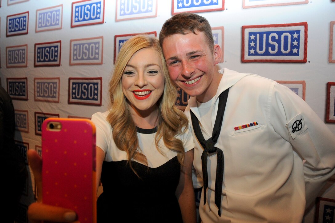 Navy Seaman Charles Boze poses with a partygoer at the Hard Rock Times Square kick off party for New York Fleet Week, May 21, 2015. Boze is a fireman assigned to the  USS San Antonio.