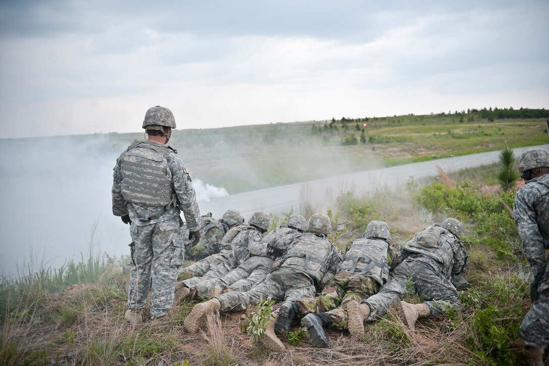 Soldiers seize the high ground to engage simulated enemy forces while the breach team moves into position on the road during a combined arms live-fire exercise on Fort Benning, Ga., May 15, 2015.