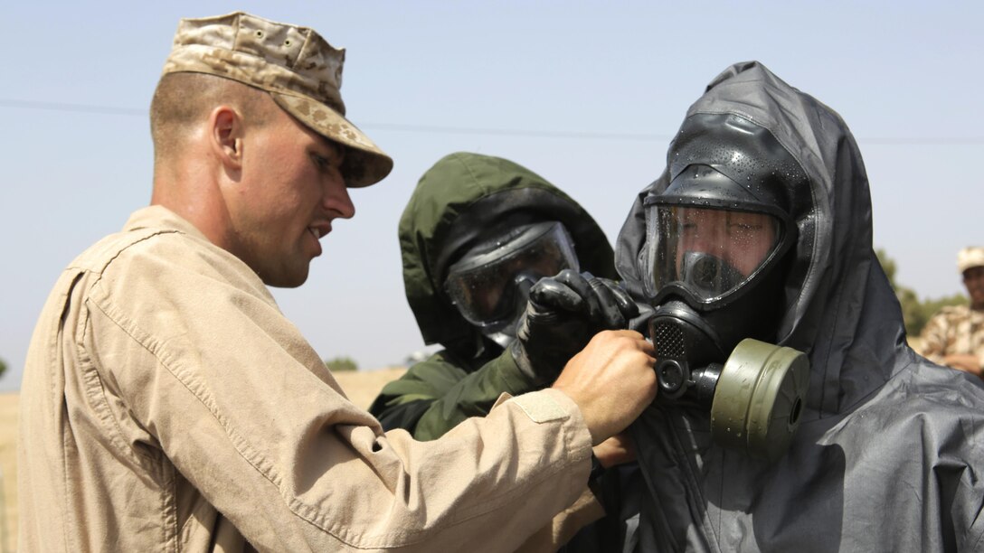 A Royal Moroccan Armed Forces soldier and U.S. Marine Corps Sgt. Brent Berven, Chemical, Biological Incident Response Force, helps Dutch 1st Soldier Peter Van Der Bourght, Netherlands Armed Forces, decontaminate his gas mask for a demonstration of Chemical, Biological, Radiological, and Nuclear defense procedures during Exercise African Lion 15 in Tifnit, Morocco, May 16. The Royal Moroccan, U.S., U.K., Netherlands, and Belgian Armed Forces integrated while conducting peacekeeping support training to improve military capabilities and operational familiarity as one international coalition.