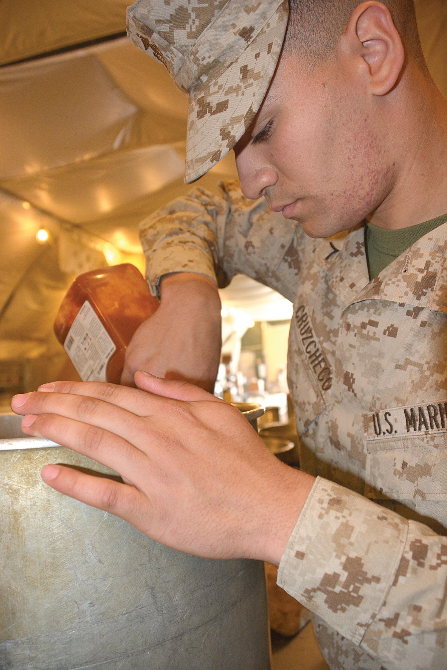 Pfc. Christopher Cruzcheco, a Marine student in class 027-15, adds creole seasoning to shrimp as part of the final meal March 24 in his training. (Photo by Amy Perry, Fort Lee Public Affairs)