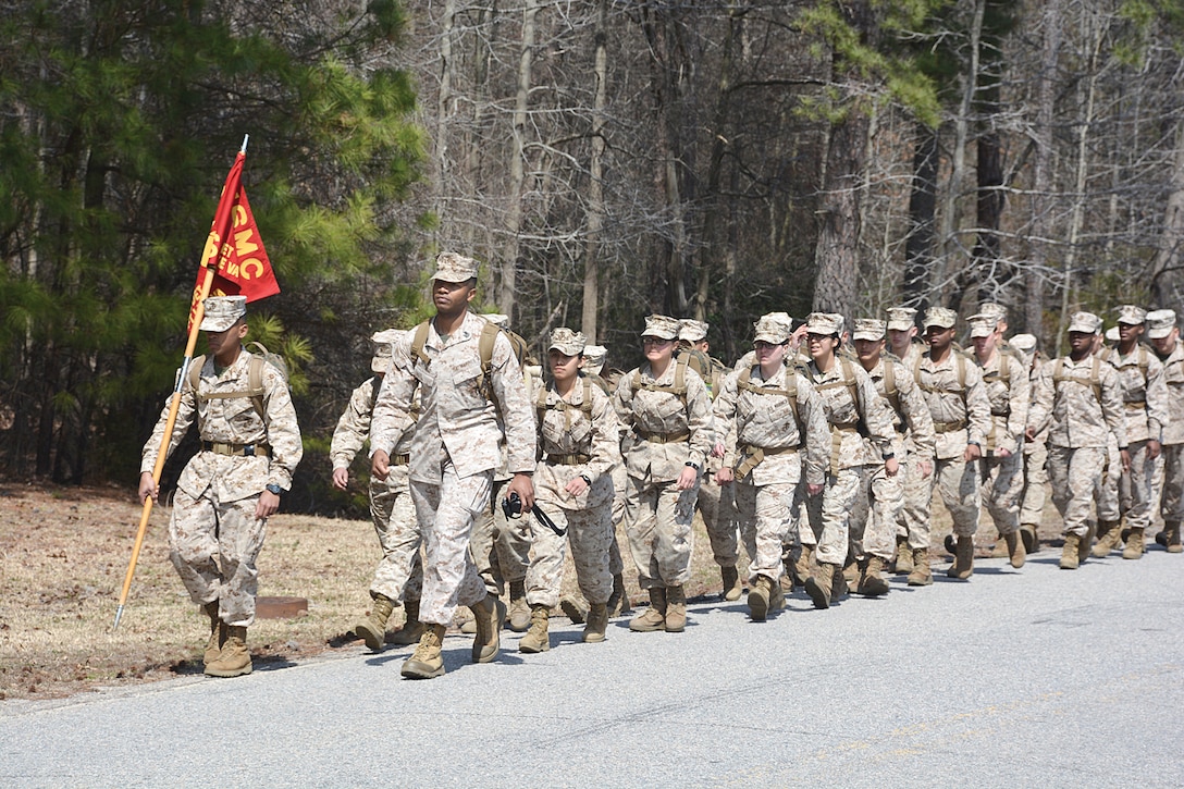 Marine Pfc. Frank Barker, guidon holder, and Gunnery Sgt. Morris Mayfield, Food Service instructor, lead Marine Food Service Class 027-15 on a 5-mile ruck march as part of a two-day event for the students' final meal project March 23. (Photo by Amy Perry, Fort Lee Public Affairs)