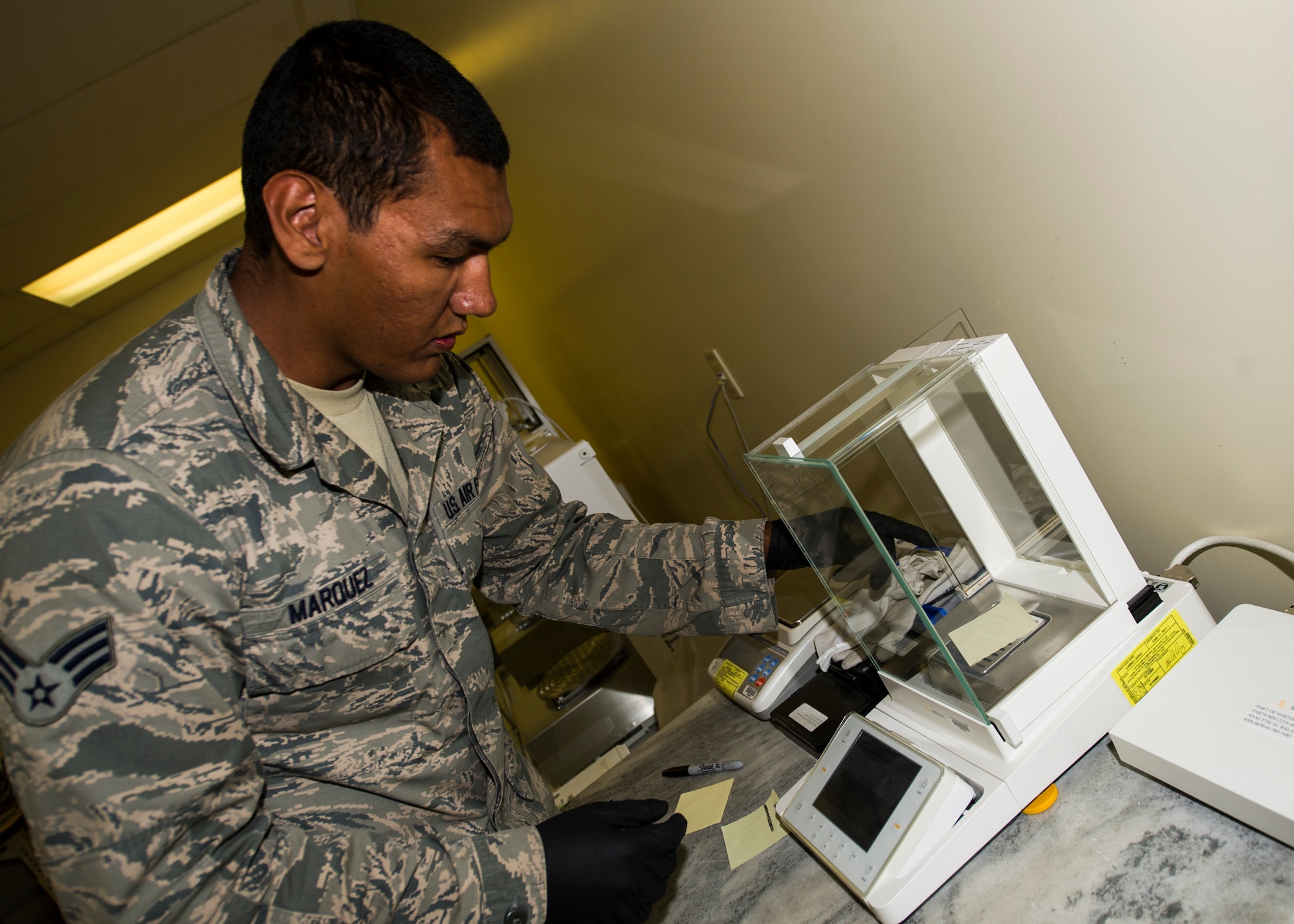 Senior Airman Troy Marquez, 49th Maintenance Squadron Precision Measurement Equipment Laboratory technician, zeros out an analytical balance at PMEL May 28, 2015 at Holloman Air Force Base, N.M. The analytical balance is an extremely accurate scale. It is so accurate that it can measure how much a signature on a sticky note weighs. (U.S. Air Force photo by Airman 1st Class Emily A. Kenney/Released)