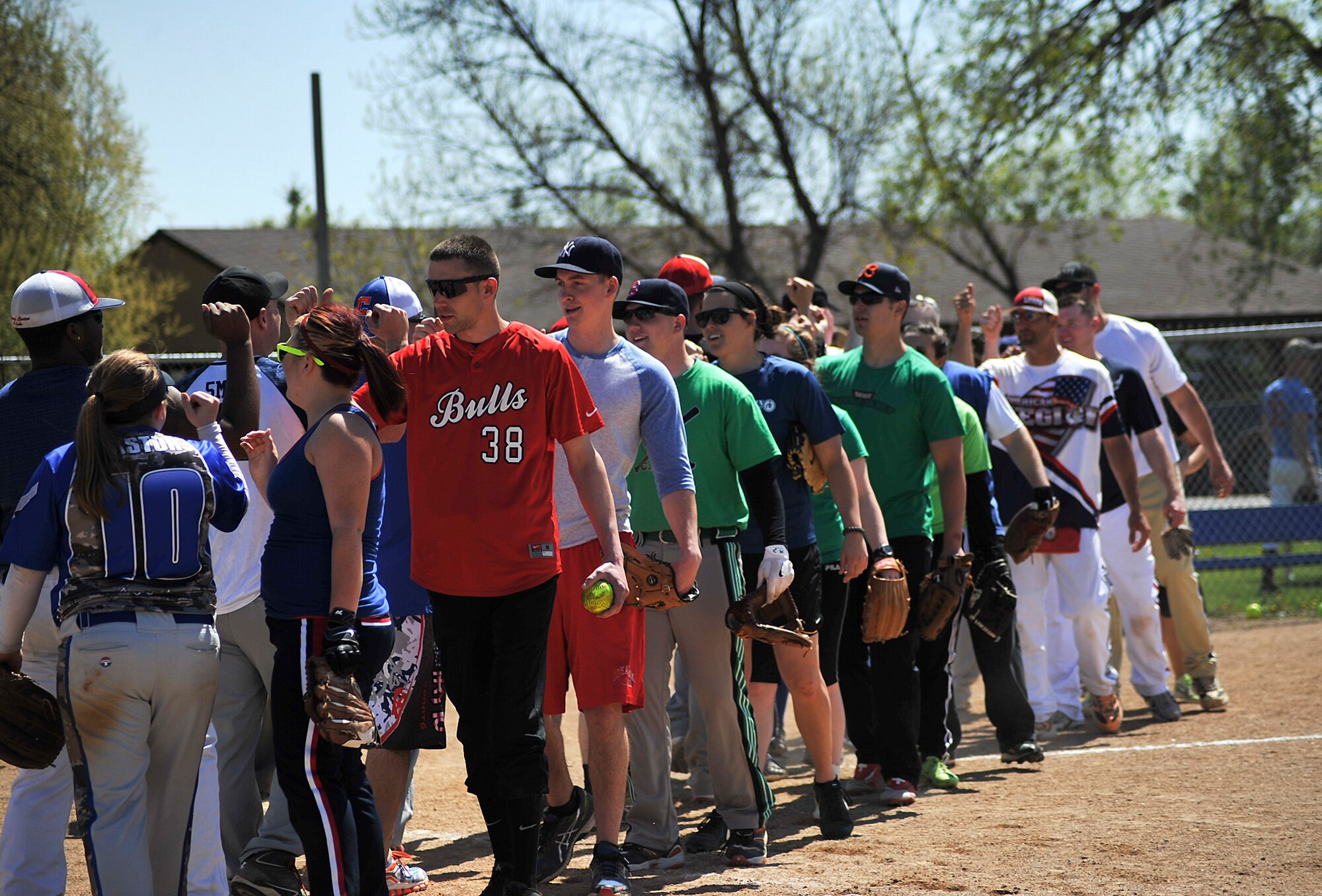Airmen from Grand Forks and Minot Air Force Bases line up to shake hands and high five each other at the end of a scrimmage game during the Minot AFB vs. Grand Forks AFB softball tournament at Roosevelt Park in Devils Lake, N.D., May 21, 2015. The tournament was the first time the two bases came together on the field of play for a morale boosting event. (U.S. Air Force photo by Airman 1st Class Bonnie Grantham/Released)