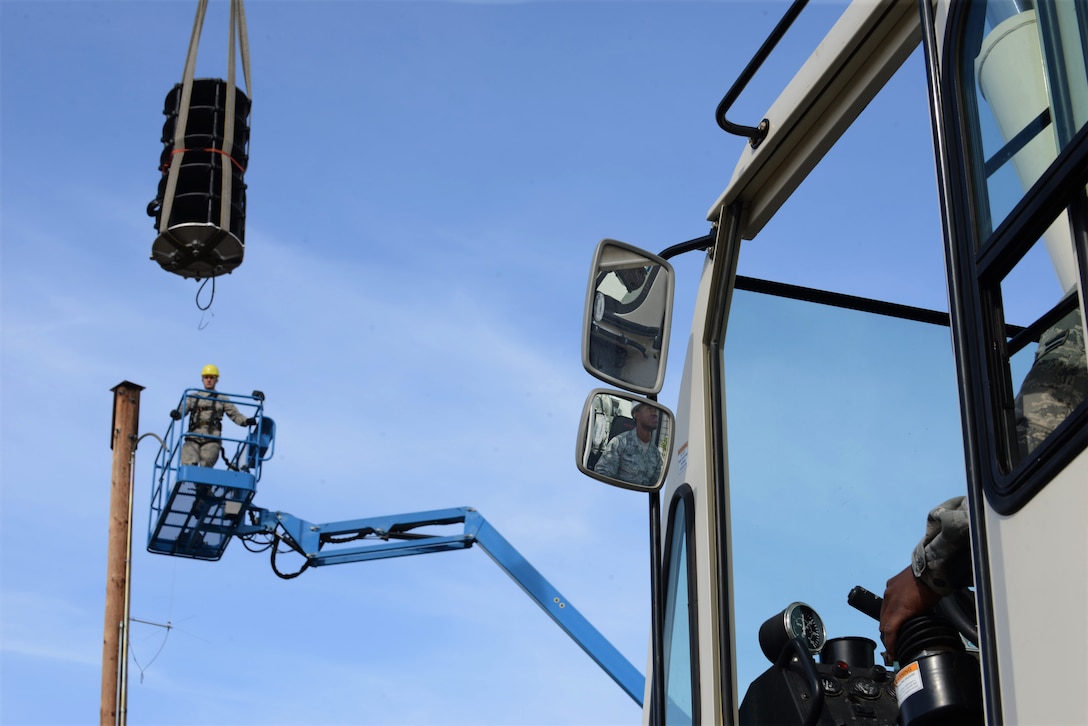 U.S. Air Force Airman 1st Class Dre Perry, a 354th Civil Engineer Squadron heavy equipment operator, slowly lifts a new Giant Voice Speaker while Airman 1st Class Devan Stutler, a 354th Communications Squadron radio frequency transmission systems apprentice, waits to remove the lifting straps May 15, 2015, at Eielson Air Force Base, Alaska. All electronics, stacks and controllers will be replaced, which should increase the effectiveness of the system by 26 percent. (U.S. Air Force photo by Senior Airman Ashley Nicole Taylor/Released)