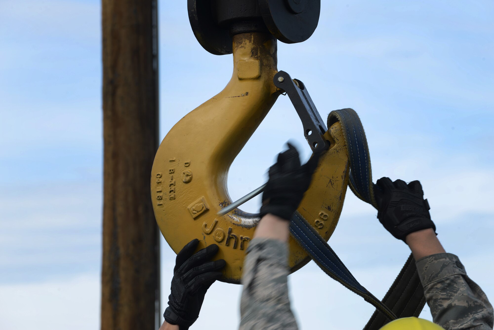 U.S. Air Force Airmen assigned to the 354th Communications Squadron (CS), secure lifting straps on a crane hook May 15, 2015, at Eielson Air Force Base, Alaska. The 354th Civil Engineer Squadron Dirt Boyz shop assisted the CS by providing crane support to remove an old Giant Voice speaker cell for replacement. (U.S. Air Force photo by Senior Airman Ashley Nicole Taylor/Released)