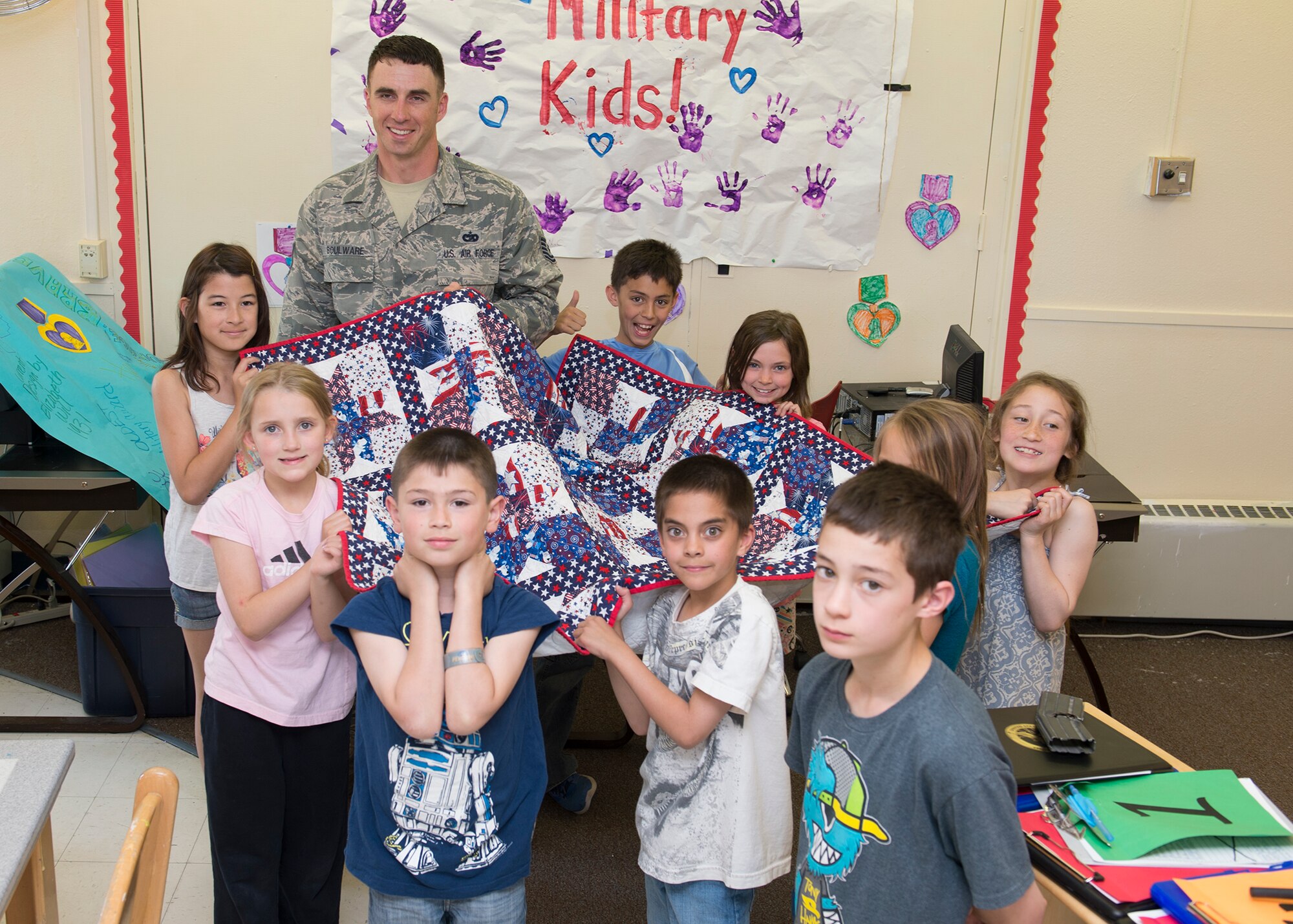 U.S. Air Force Tech. Sgt. Jimmy Boulware, a 354th Logistics Readiness Squadron quality assurance inspector, is given a certified Quilt of Valor, May 27, 2015, sewed by school age program students over the course of six months at Eielson Air Force Base, Alaska. The students used the opportunity to show gratitude for Boulware who explained the importance of the Purple Heart he earned while deployed after he was injured in an improvised explosive device blast in 2005. (U.S. Air Force photo by Staff Sgt. Shawn Nickel/Released)