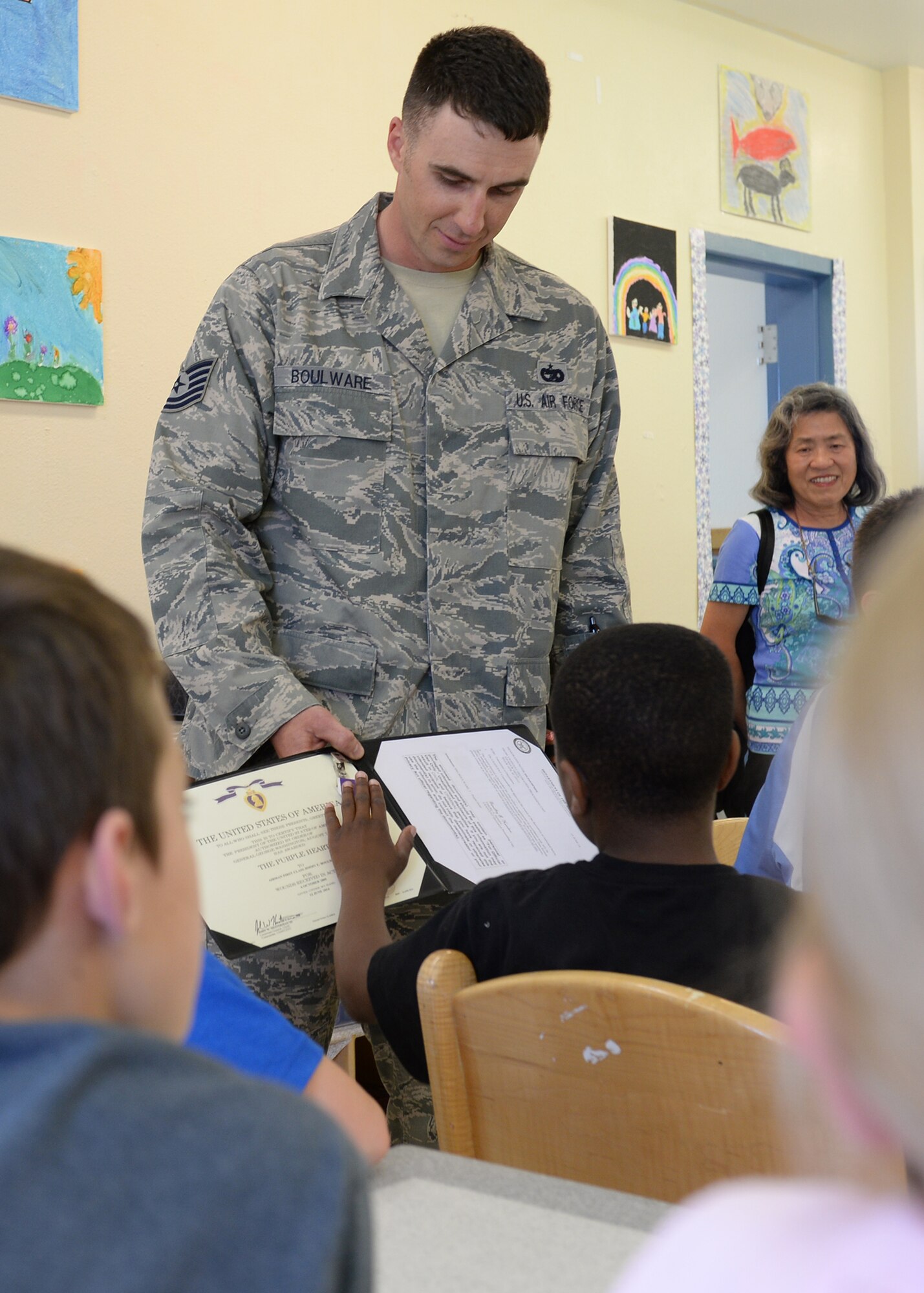 U.S. Air Force Tech. Sgt. Jimmy Boulware, a 354th Logistics Readiness Squadron quality assurance inspector, shows his Purple Heart to students during a presentation at the school age program May 27, 2015, on Eielson Air Force Base, Alaska. The students were learning about the significance of the medal along with the history of President George Washington who founded the oldest award still presented to U.S. military members. (U.S. Air Force photo by Staff Sgt. Shawn Nickel/Released)
