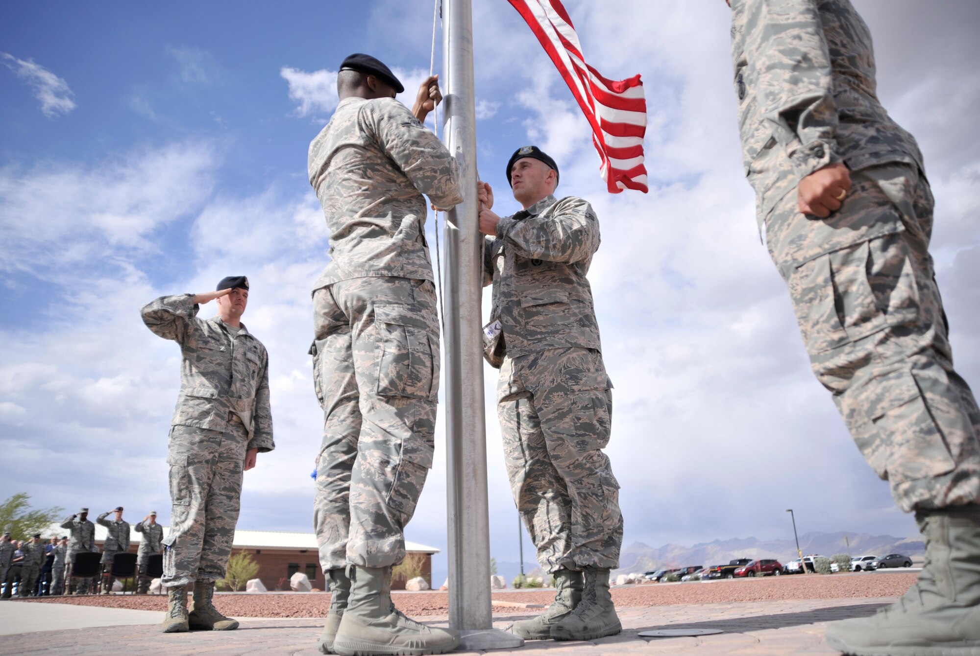 Members of the 799th Security Forces Squadron lower the flag during a retreat ceremony May 14, 2015, at Creech Air Force Base, Nevada. The ceremony took place during National Police Week which honors the fallen law enforcement officers who have paid the ultimate sacrifice. (U.S. Air Force photo by Airman 1st Class Christian Clausen/Released))