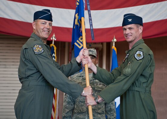 Col. Michael Drowley (right), U.S. Air Force Weapons School commandant, accepts the USAFWS guidon from Brig. Gen. Christopher Short, 57th Wing commander, during the USAFWS’s change of command ceremony at Nellis Air Force Base, Nev., May 26, 2015. The passing of the guidon signals the official start of the new commander’s tenure in charge. (U.S. Air Force photo by Staff Sgt. Siuta B. Ika)