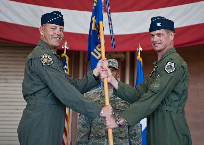 Col. Michael Drowley (right), U.S. Air Force Weapons School commandant, accepts the USAFWS guidon from Brig. Gen. Christopher Short, 57th Wing commander, during the USAFWS’s change of command ceremony at Nellis Air Force Base, Nev., May 26, 2015. The passing of the guidon signals the official start of the new commander’s tenure in charge. (U.S. Air Force photo by Staff Sgt. Siuta B. Ika)