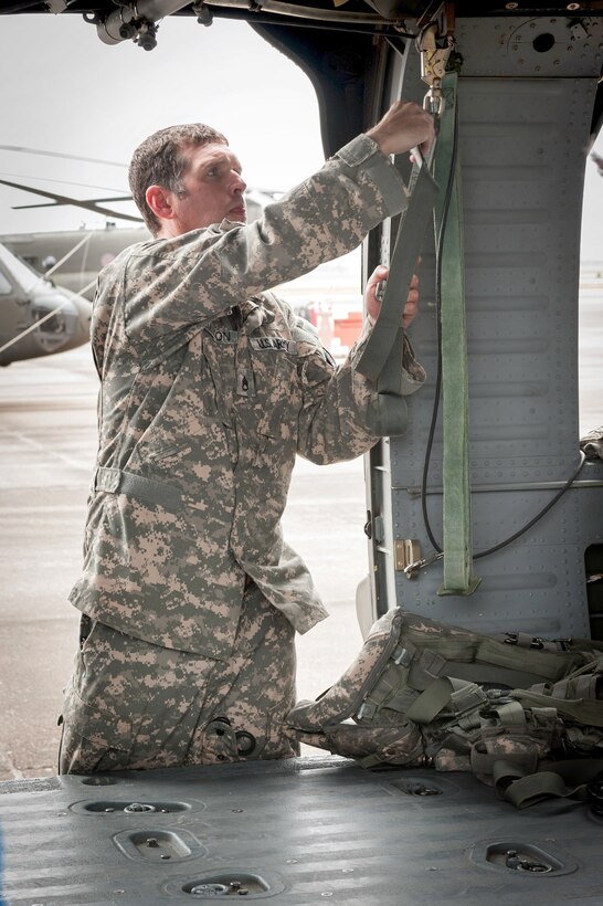 Army Sgt. Michael Hamilton prepares his UH-60 Black Hawk helicopter with rescue gear in preparation for possible swift water rescues near Houston, Texas, May 17, 2015. Hamilton is a flight medics assigned to the Louisiana National Guard. 
