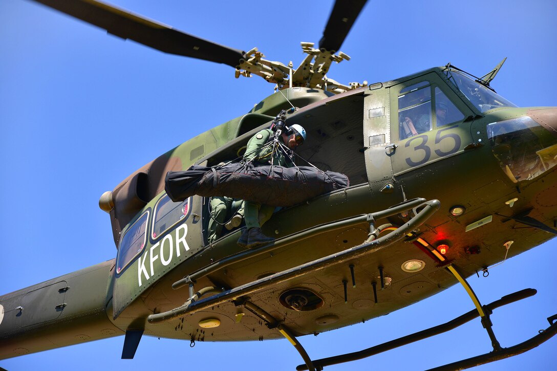 Slovenian airmen demonstrate aerial medical evacuation using a Jungle Penetrator hoist as U.S. Army paratroopers look on during the Neptune Thrust exercise at Pocek Range in Postonja, Slovenia, May 18, 2015.