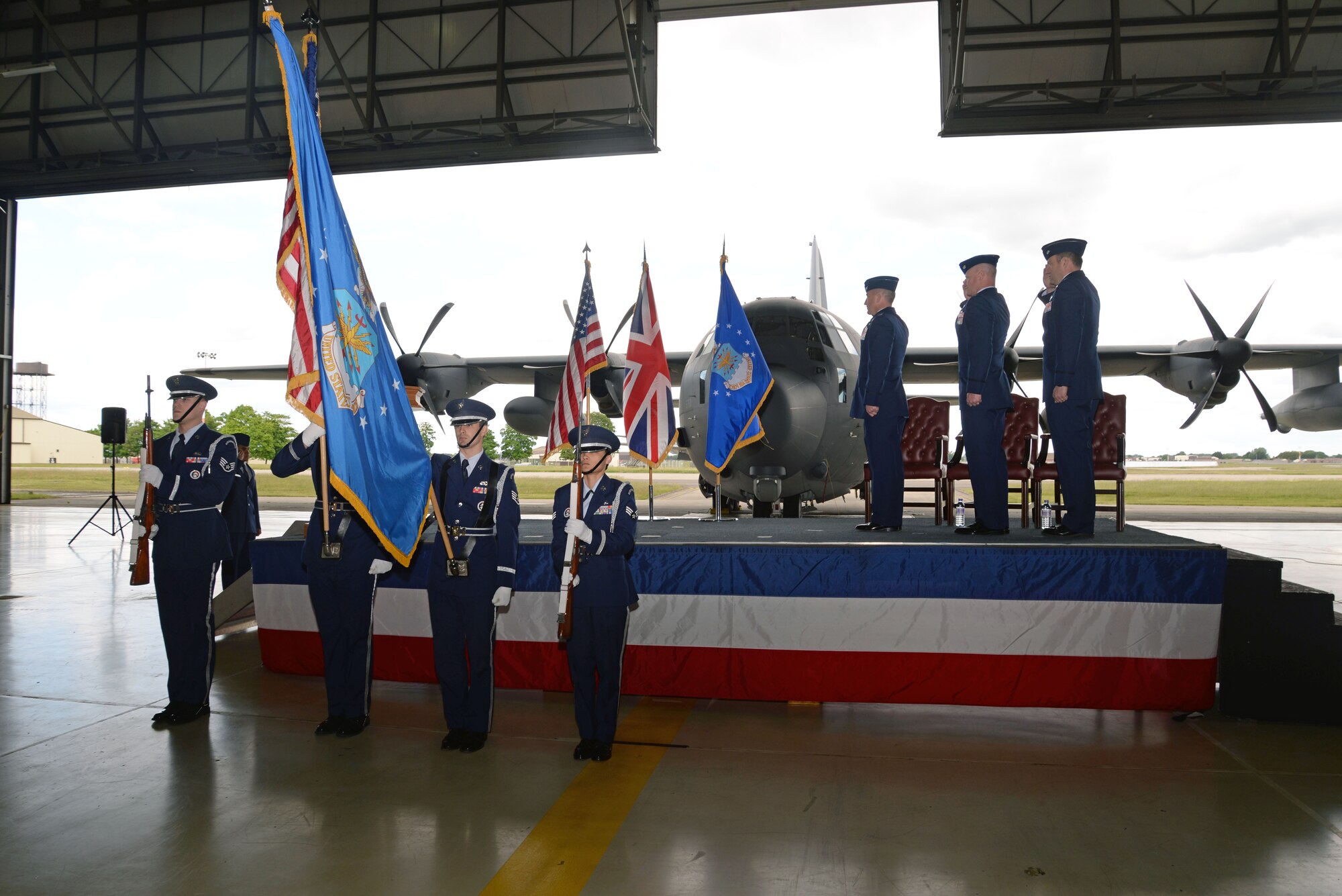The RAF Mildenhall Honor Guard presents the colors as leadership renders a salute during the playing of the U.S. and U.K. national anthems just prior to the 67th Special Operations Squadron change of command ceremony May 28, 2015, in Hangar 803 on RAF Mildenhall, England. The ceremony is a time-honored tradition in which one officer relinquishes command and passes it to another.(U.S. Air Force photo by Senior Airman Christine Halan)