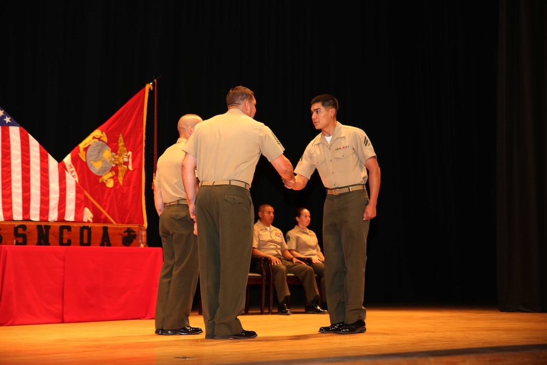 Cpl. Sergio J. Parada, right, tank repair technician, Tank Platoon, Company B, Ground Combat Element Integrated Task Force, is congratulated by Master Sgt. James Slife III, guest speaker, during the Corporal’s Course graduation at the Marine Corps Base Camp Lejeune Theater, May 28. From October 2014 to July 2015, the GCEITF conducted individual and collective level skills training in designated ground combat arms occupational specialties in order to facilitate the standards-based assessment of the physical performance of Marines in a simulated operating environment performing specific ground combat arms tasks. (U.S. Marine Corps photo by Cpl. Paul S. Martinez/Released)