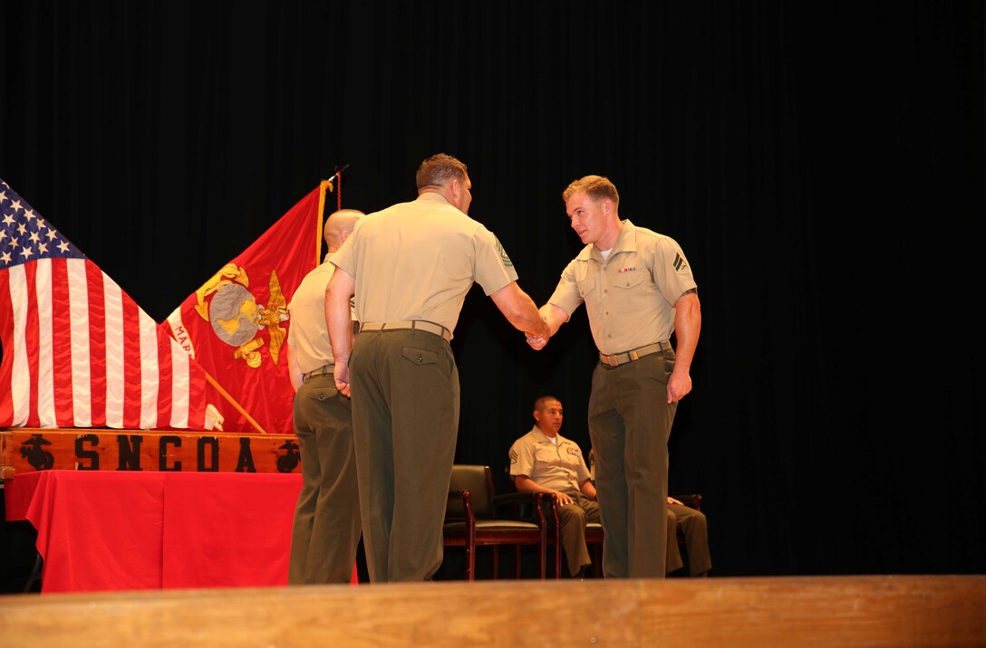 Cpl. Wesley A. Hunt, right, field artillery cannoneer, Battery A, Ground Combat Element Integrated Task Force, is congratulated by Master Sgt. James Slife III, guest speaker, during the Corporal’s Course graduation at the Marine Corps Base Camp Lejeune Theater, May 28. From October 2014 to July 2015, the GCEITF conducted individual and collective level skills training in designated ground combat arms occupational specialties in order to facilitate the standards-based assessment of the physical performance of Marines in a simulated operating environment performing specific ground combat arms tasks. (U.S. Marine Corps photo by Cpl. Paul S. Martinez/Released) 