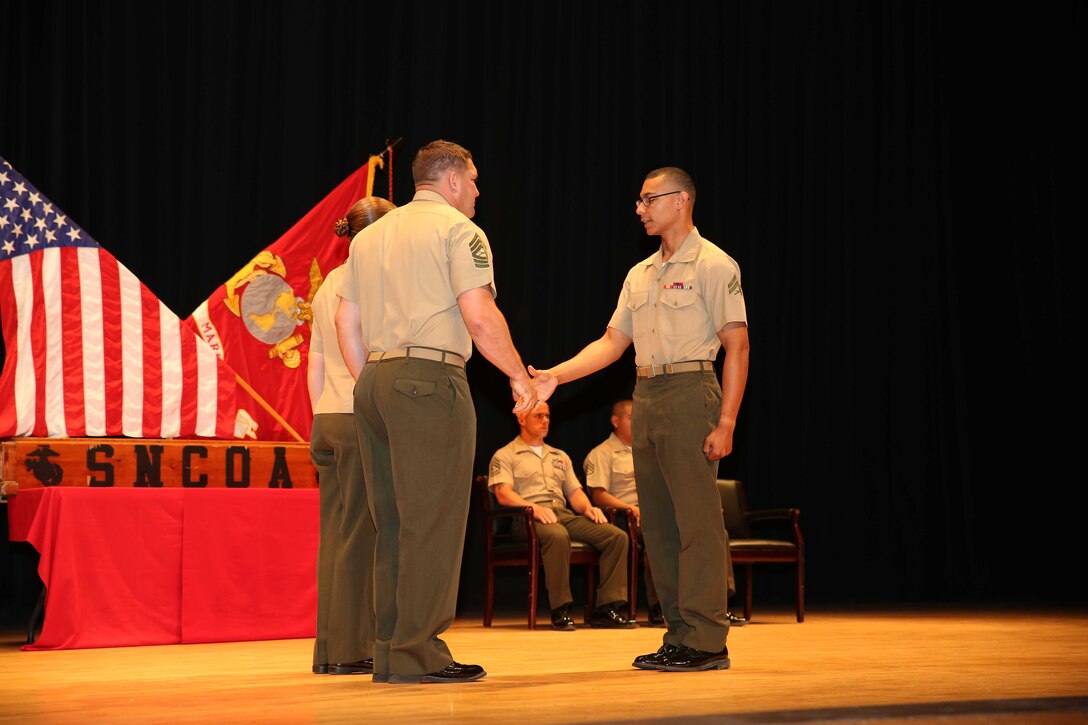 Cpl. Collin A. Bly, right, field artillery cannoneer, Battery A, Ground Combat Element Integrated Task Force, is congratulated by Master Sgt. James Slife III, guest speaker, during the Corporal’s Course graduation at the Marine Corps Base Camp Lejeune Theater, May 28. From October 2014 to July 2015, the GCEITF conducted individual and collective level skills training in designated ground combat arms occupational specialties in order to facilitate the standards-based assessment of the physical performance of Marines in a simulated operating environment performing specific ground combat arms tasks. (U.S. Marine Corps photo by Cpl. Paul S. Martinez/Released)  