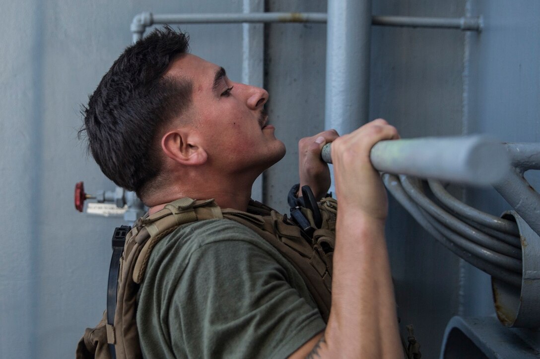 U.S. Marine Lance Cpl. Joseph Burke does a pull-up to honor fallen service members during physical training aboard the USS Rushmore (LSD 47) at sea in the Pacific Ocean, May 25, 2015. Burke is a team leader with Kilo Compnay, Battalion Landing Team 3rd Battalion, 1st Marine Regiment, 15th Marine Expeditionary Unit. In honor of Memorial Day, Marines with BLT 3/1 ran the ‘Memorial Day Murph’ challenge. The physical fitness event is named after Medal of Honor recipient U.S. Navy Lt. Michael P. Murphy. The challenge developed from Murphy’s daily work out routine, which consisted of a one-mile run, 100 pull-ups, 200 push-ups, 300 squats, and finishing with another one-mile run.  (U.S. Marine Corps photo by Sgt. Emmanuel Ramos/Released)