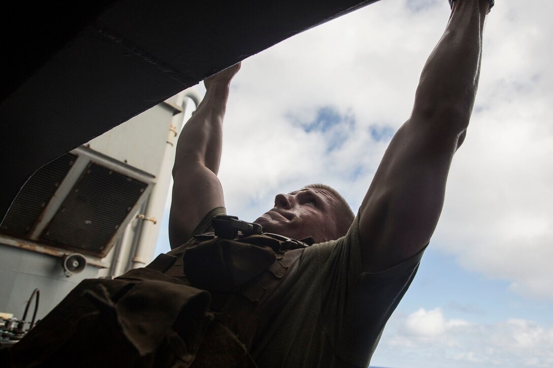 U.S. Marine Brian Dodman does a pull-up to honor fallen service members during physical training aboard the USS Rushmore (LSD 47) at sea in the Pacific Ocean, May 25, 2015. Dodman is a team leader with Kilo Compnay, Battalion Landing Team 3rd Battalion, 1st Marine Regiment, 15th Marine Expeditionary Unit. In honor of Memorial Day, Marines with BLT 3/1 ran the ‘Memorial Day Murph’ challenge. The physical fitness event is named after Medal of Honor recipient U.S. Navy Lt. Michael P. Murphy. The challenge developed from Murphy’s daily work out routine, which consisted of a one-mile run, 100 pull-ups, 200 push-ups, 300 squats, and finishing with another one-mile run.  (U.S. Marine Corps photo by Sgt. Emmanuel Ramos/Released)