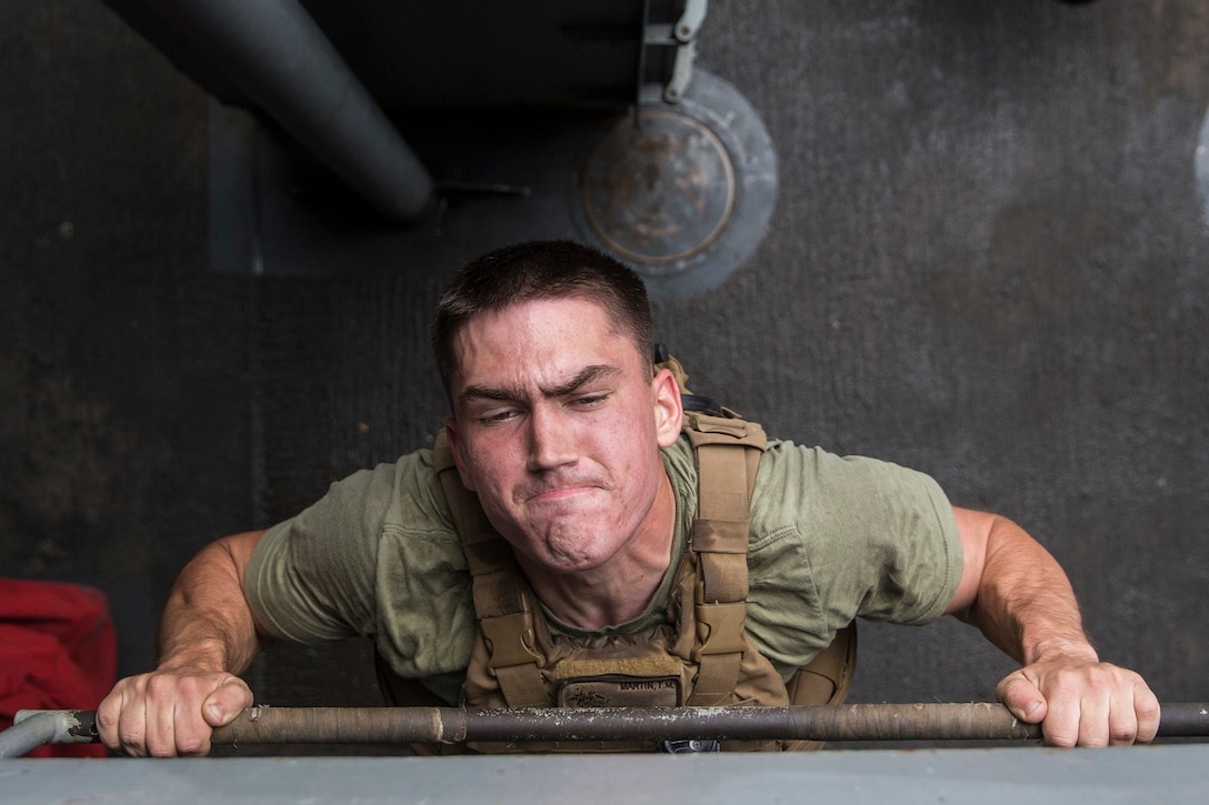 U.S. Marine Lance Cpl. Trent Martin does a pull-up to honor fallen service members during physical training aboard the USS Rushmore (LSD 47) at sea in the Pacific Ocean, May 25, 2015. Martin is an automatic rifleman with Kilo Compnay, Battalion Landing Team 3rd Battalion, 1st Marine Regiment, 15th Marine Expeditionary Unit. In honor of Memorial Day, Marines with BLT 3/1 ran the ‘Memorial Day Murph’ challenge. The physical fitness event is named after Medal of Honor recipient U.S. Navy Lt. Michael P. Murphy. The challenge developed from Murphy’s daily work out routine, which consisted of a one-mile run, 100 pull-ups, 200 push-ups, 300 squats, and finishing with another one-mile run.  (U.S. Marine Corps photo by Sgt. Emmanuel Ramos/Released)