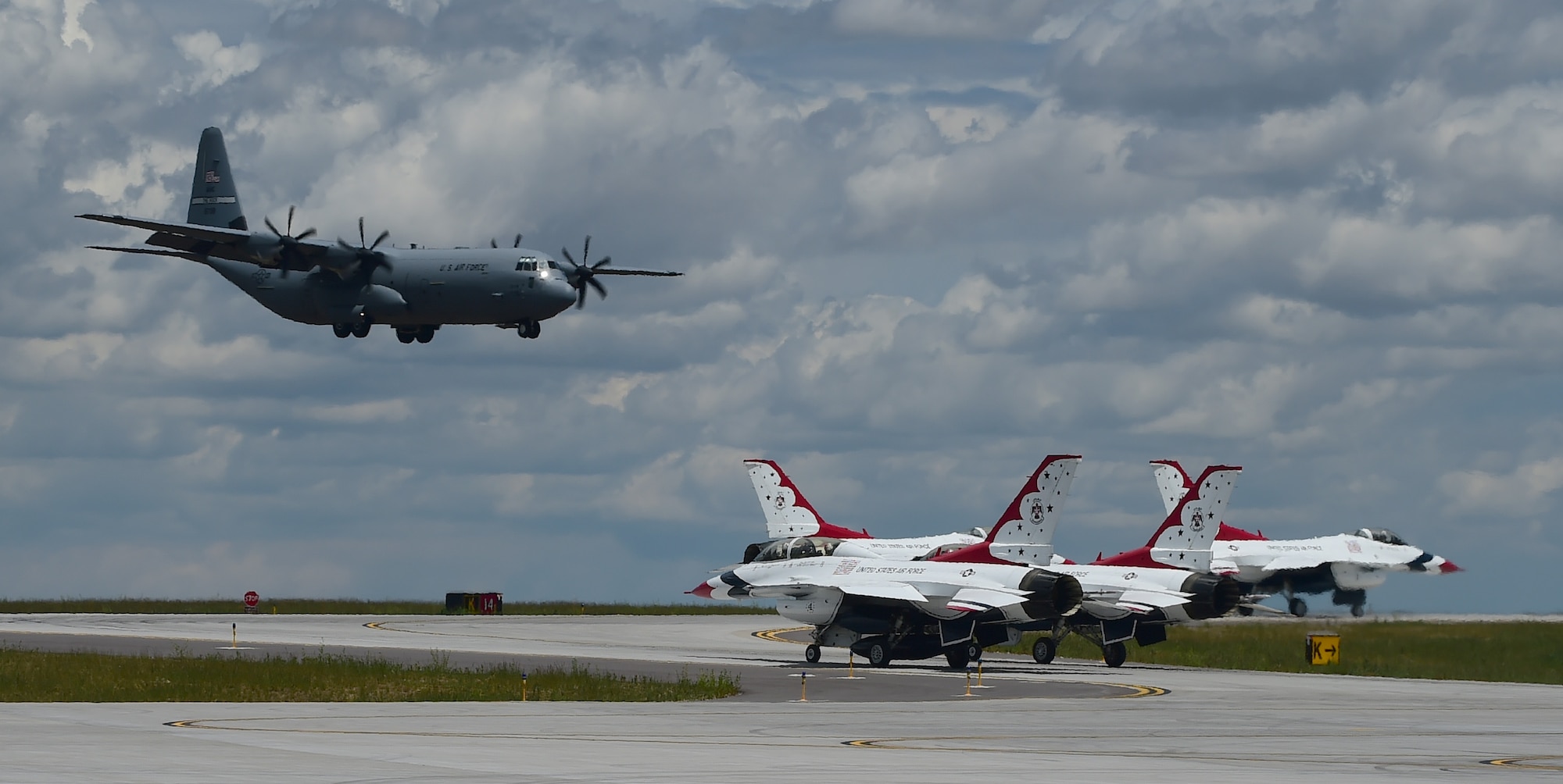 A C-130J Super Hercules lands as Thunderbird jets taxi May 29, 2015 on Buckley Air Force Base, Colo. The Thunderbirds are staging out of Buckley AFB for the up-coming Rocky Mountain Air Show. (U.S. Air Force photo by Airman 1st Class Luke W. Nowakowski/Released)