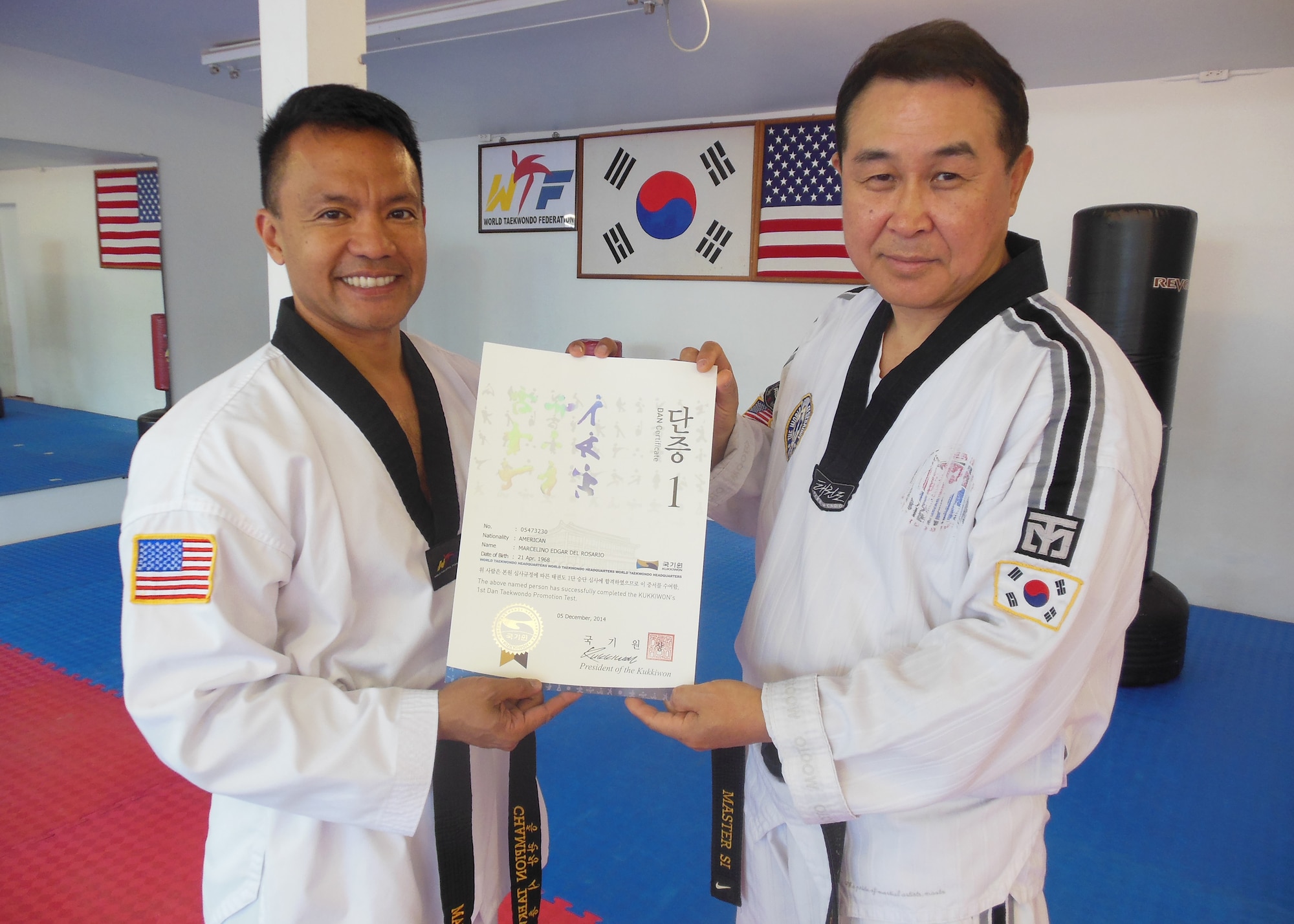 Col. Marc Del Rosario, 30th Operations Group commander, receives a promotion certificate from Choong Man Si, Tae Kwon Do Grand Master, Dec. 5, 2014, Lompoc, Calif. Del Rosario, who recently received his black belt in Tae Kwon Do, attributes the studio and his mentor for his excellent fitness status. (Courtesy photo)