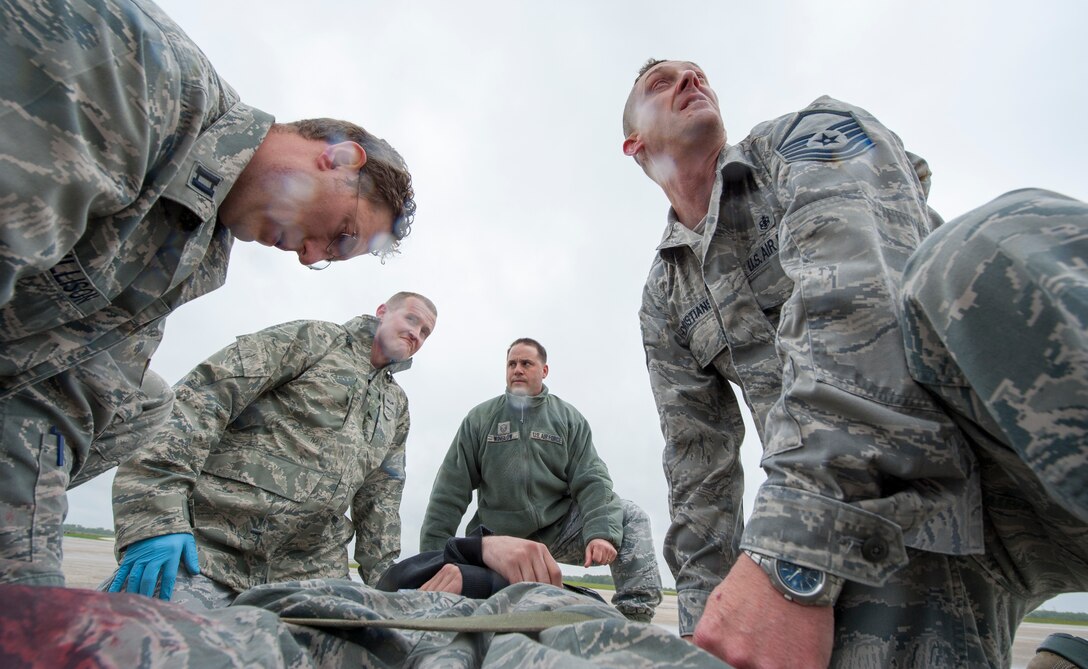 Members of the 509th Medical Group strap a simulated aircraft accident victim to a stretcher during a major accident response exercise May 20, 2015, at Whiteman Air Force Base, Mo. During exercises like these, medics who might not normally treat patients together are tested on their ability to quickly and efficiently work as a team. (U.S. Air Force photo by Staff Sgt. Brigitte N. Brantley/Released)