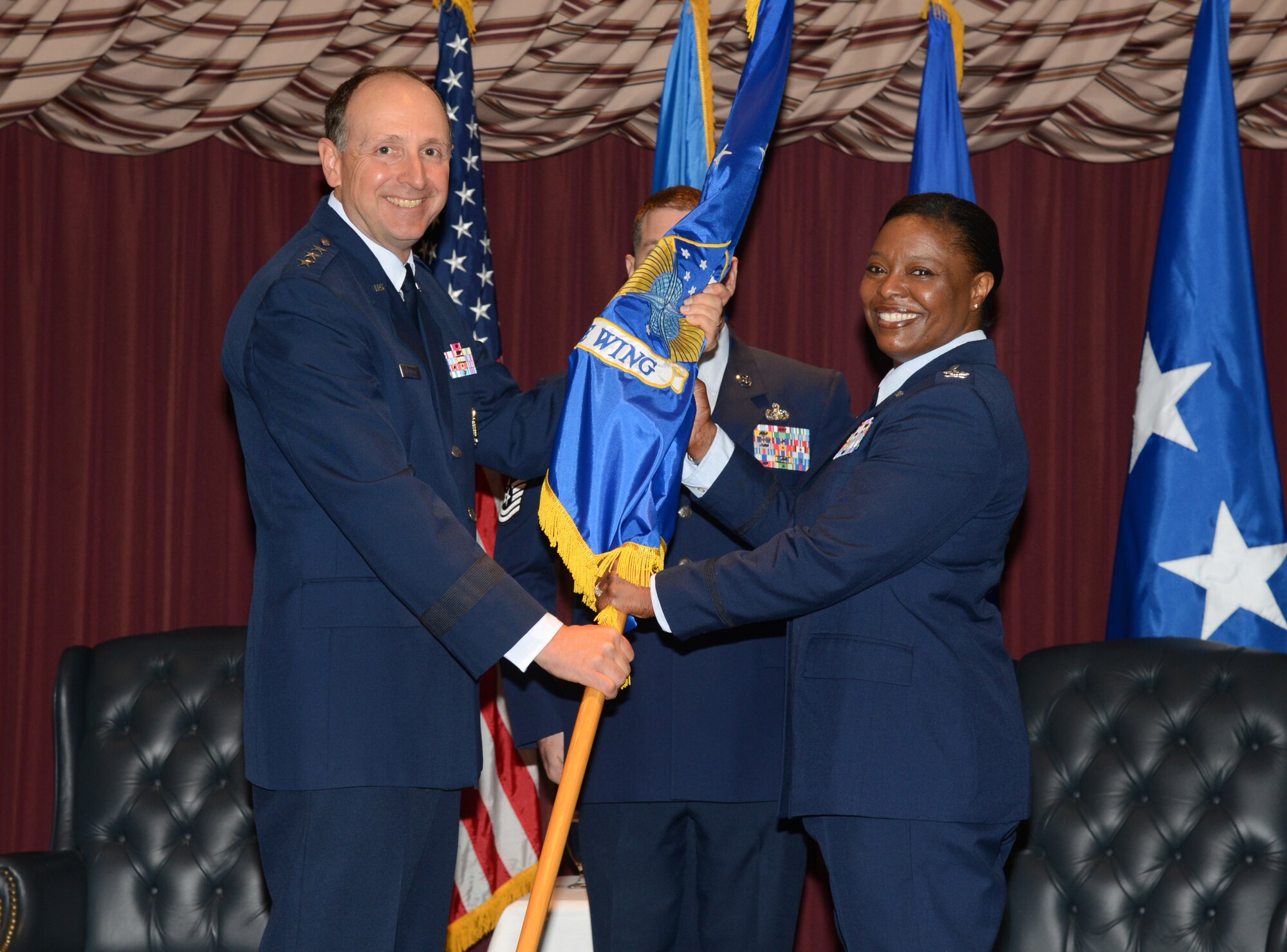 Lt. Gen Bruce Litchfield, Air Force Sustainment Center commander, passes command of the 72nd Air Base Wing to Col. Stephanie Wilson during a change of command ceremony Wednesday at Tinker Air Force Base. Chief Master Sgt. Thomas Christopher, 72nd Air Base Wing command chief, stands ready to receive the ceremonial guidon from the new commander. Colonel Wilson succeeds Col. Christopher Azzano, who will command the 96th Test Wing at Eglin AFB, Fla. As the 72nd Air Base Wing and Installation Commander, Colonel Wilson is responsible for a $311 million operating budget and more than 3,000 personnel providing a wide range of installation support services enabling a diverse group of National Defense missions.  (Air Force photo by Kelly White/Released)