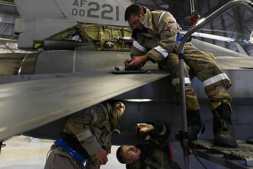 U.S. Air Force Senior Airman Gage Welsh (top), Senior Airman Christopher Smith (bottom left), and Airman 1st Class Gage Moak, 20th Equipment Maintenance Squadron phase inspection team members, repair an F-16CM Fighting Falcon during operational readiness exercise Weasel Victory 15-06 at Shaw Air Force Base, S.C., May 28, 2015. OREs are integrated into training on bases to ensure Airmen are combat readiness. (U.S. Air Force photo by Senior Airman Diana M. Cossaboom/Released)