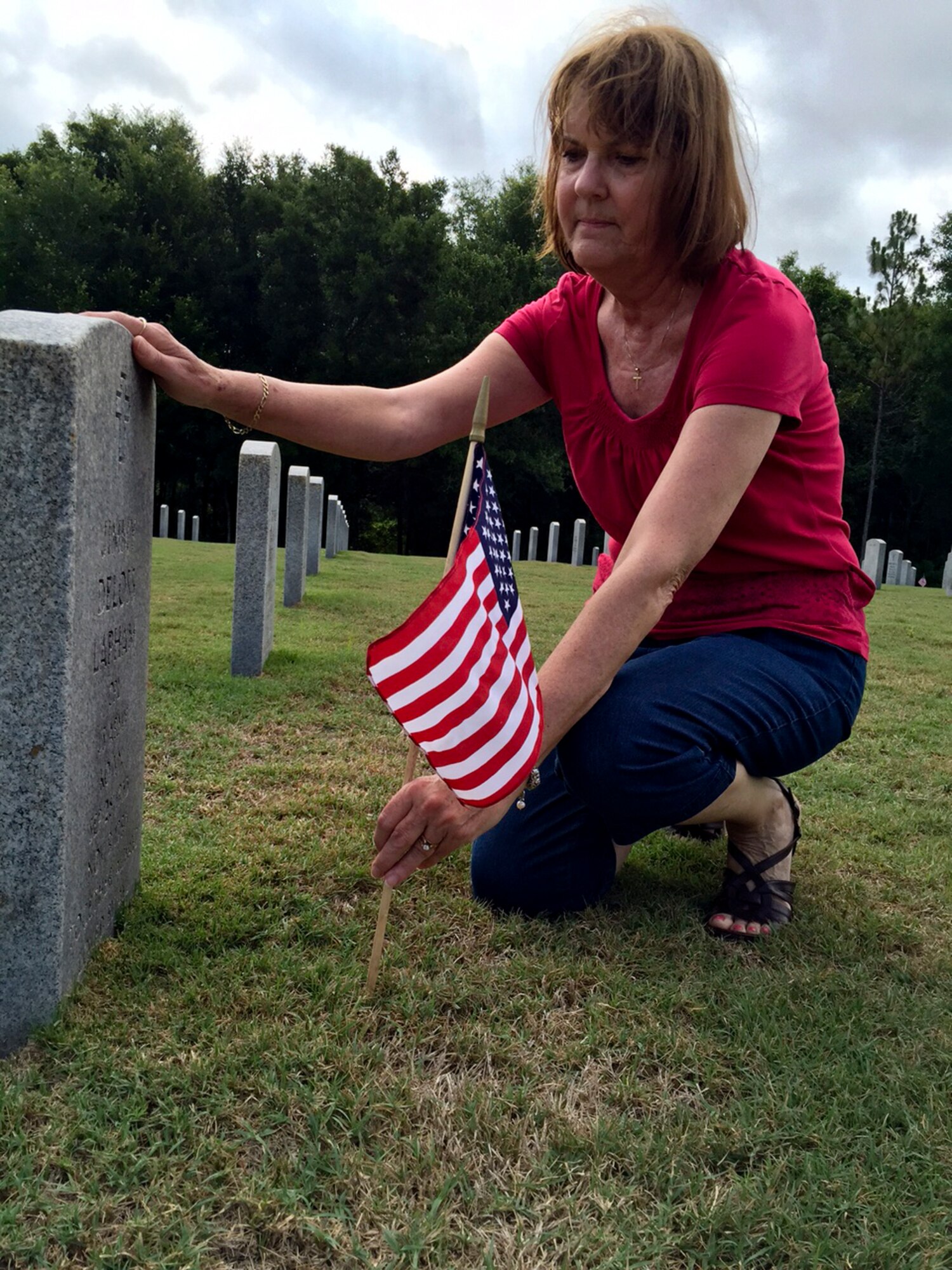 Tina Lacey places an American flag in front of her father’s headstone in honor of Memorial Day at Florida National Cemetery in Bushnell, Fla., May 24, 2015. Memorial Day falls on the last Monday of the month and is reserved as a day of remembrance for those who honorably served in the military. (U.S. Air Force photo by Senior Airman Bulow-Gonterman/Released)    