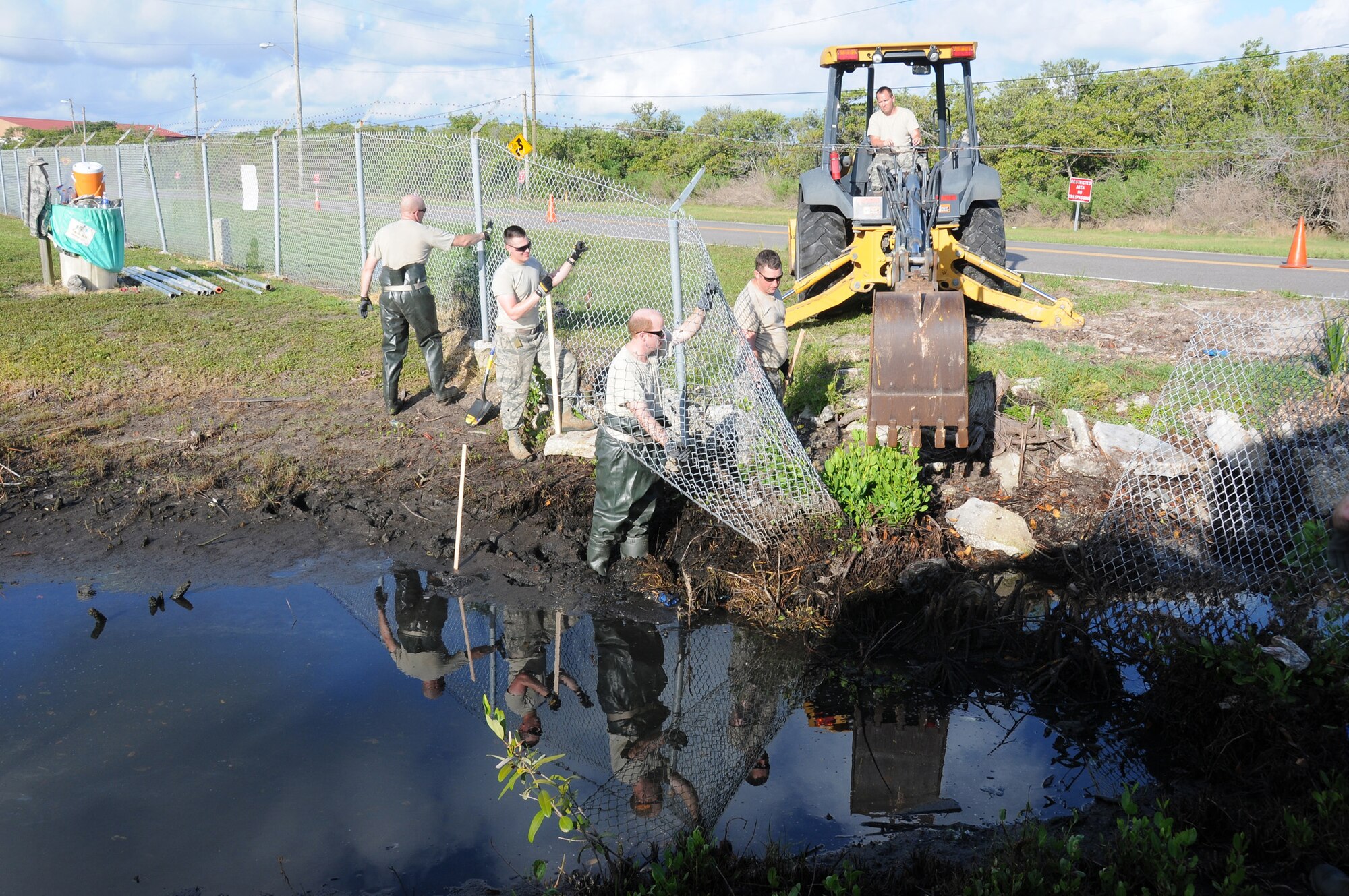 A picture of U.S. Air Force Airmen removing a fence and cleaning out a drainage ditch.