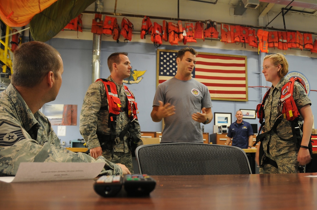 U.S. Air Force Airmen from the New Jersey Air National Guard’s 177th Civil Engineering Squadron meet with Coast Guard Petty Officer 3rd Class Spencer Caraballo, aviation survival technician, for a brief on water survival equipment at Coast Guard Air Station Clearwater, Fla., on May 19, 2015. Airmen from the 177th Fighter Wing were preparing for the opportunity to assist the Coast Guard by acting as survivors during their search and rescue training. (U.S. Air National Guard photo by Airman 1st Class Amber Powell/Released)