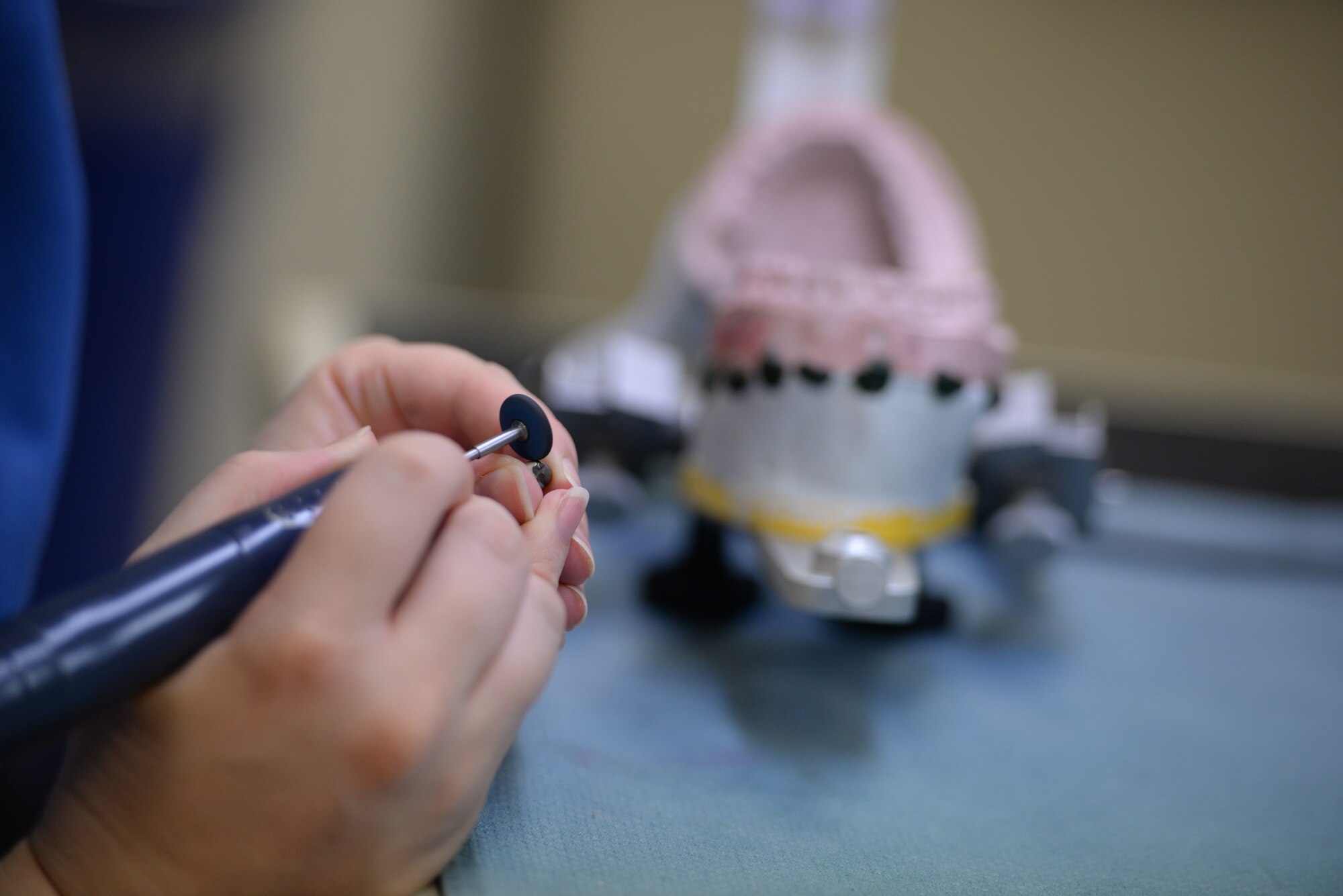 An 18th Dental Squadron dental lab technician polishes a metal dental crown on Kadena Air Base, Japan, May 29, 2015. The 18th DS’s Area Dental Lab supports more than 52 dental units across the Pacific Command. (U.S. Air Force photo by Senior Airman Omari Bernard)