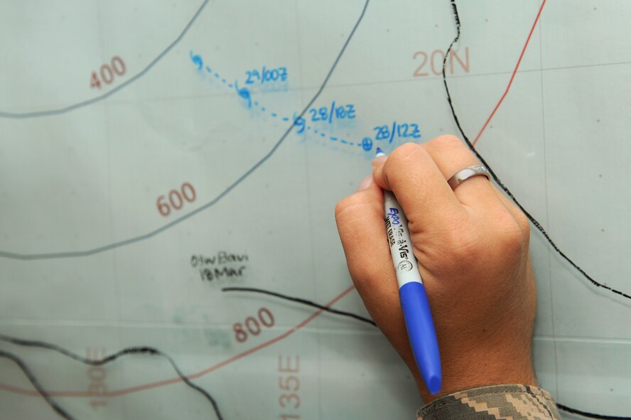 An 18th Operations Support Squadron weather technician, demonstrates how to plot the path of a typhoon on Kadena Air Base, Japan, May 29, 2015. During typhoon season, 18th OSS weather flight personnel monitor all storm activity in the Pacific theater in order to alert Kadena personnel and their families of any potential typhoons that could affect Okinawa. (U.S. Air Force photo by Airman 1st Class Zade C. Vadnais)