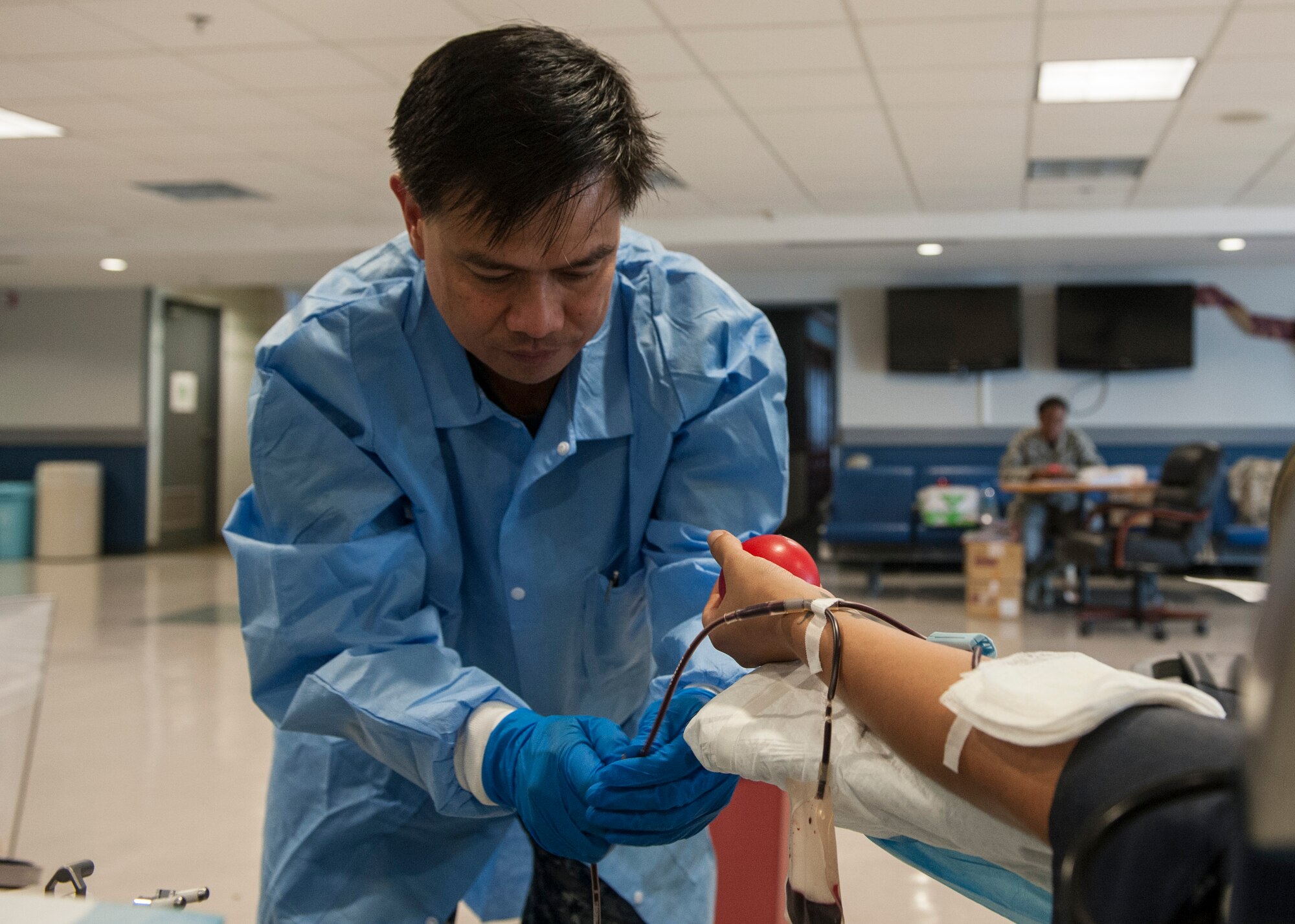 U.S. Navy Petty Officer 1st Class Christian Lacson, U.S. Naval Hospital, Okinawa, laboratory technician, adjusts a blood line during the Pacesetter post-Memorial Day blood drive on Kadena Air Base, Japan, May 29, 2015. One pint of blood can save up to three lives, and the blood drive is a way for military members to help give to those in need. (U.S. Air Force photo by Senior Airman Stephen Eigel) 