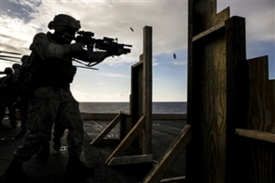 A U.S. Marine shoots at targets on the flight deck of the USS Essex in the Pacific Ocean, May 28, 2015. The Marine is assigned to the 15th Marine Expeditionary Unit’s Maritime Raid Force. The drill simulates entering a room and immediately seeing a target. 