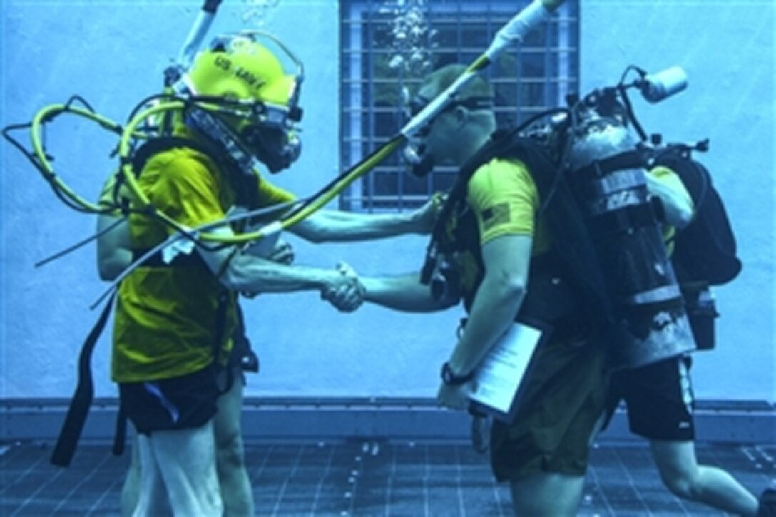 Navy Secretary Ray Mabus presents an award to Marine Corps Gunnery Sgt. Bo Irving, a combatant diver course instructor, in the aquatic training facility at Naval Diving and Salvage Training Center in Panama City, Fla., May 27, 2015. The center is the largest diving training facility in the world.