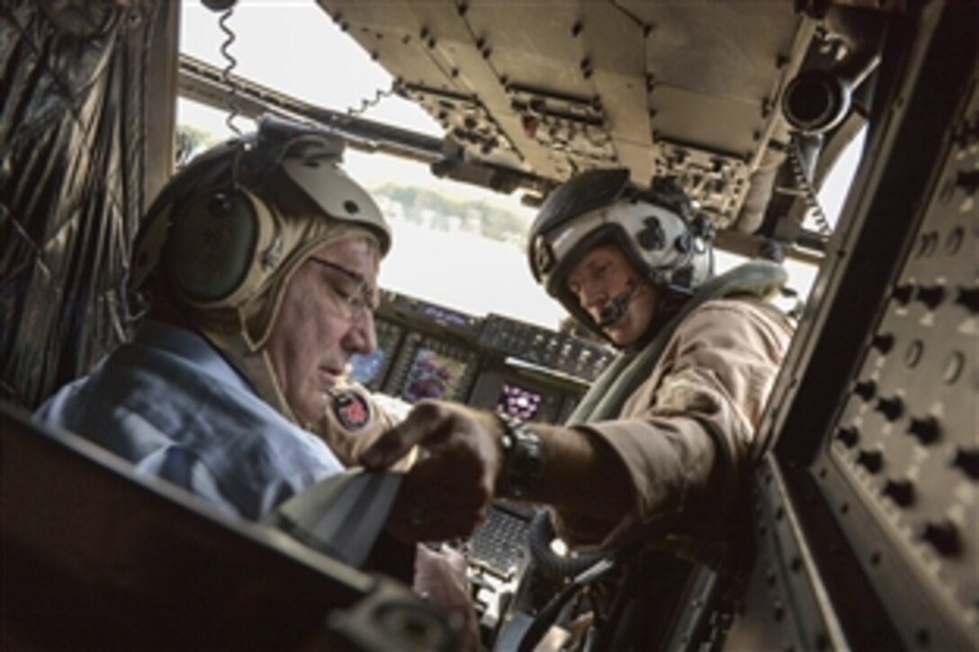 A U.S. Marine Corps pilot straps U.S. Defense Secretary Ash Carter into his seat on an MV-22 Osprey before surveying the Straits of Malacca off the coast of Singapore, May 29, 2015. Carter is visiting the Asia-Pacific region to strengthen relationships and modernize U.S. alliances.