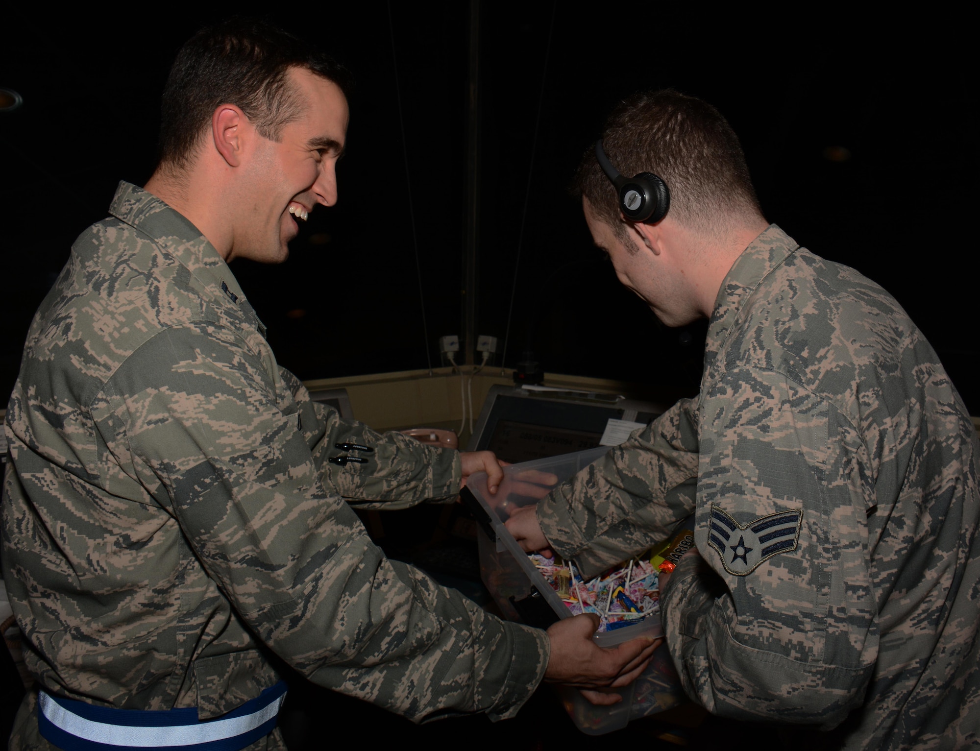 379th Air Expeditionary Wing Chaplain (Capt.) Christopher De Luise, offers candy to a 379th Expeditionary Operations Support Squadron air traffic controller inside the tower at Al Udeid Air Base, Qatar Oct. 31 during a chaplain led Blitz Program visit. The program focuses on visiting shift workers and informing those airmen of the resources available to them. More than 20 professionals took part in the Halloween visit with 379th Expeditionary Operations Group airmen. (U.S. Air Force photo by Tech. Sgt. James Hodgman)