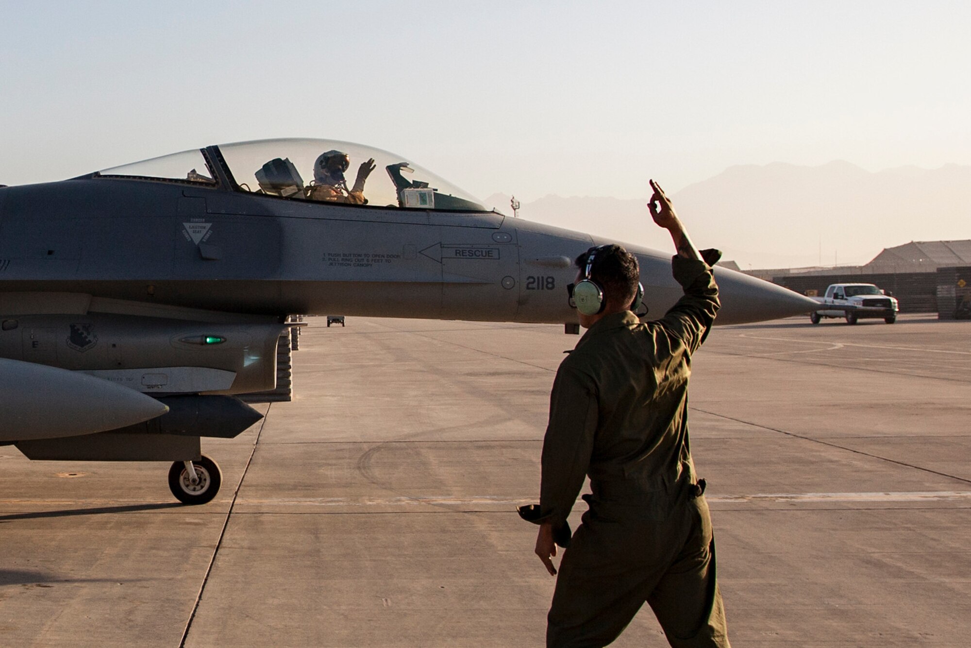 Senior Airman Zachary Machuca, 455th Expeditionary Aircraft Maintenance Squadron assistant dedicated crew chief , and a F-16 Fighting Falcon pilot signal “World Famous” as the aircraft taxies out of the parking spot to complete an air tasking order combat mission from Bagram Airfield, Afghanistan, Sept. 2, 2015.  The F-16 is a multi-role fighter aircraft that is highly maneuverable and has proven itself in air-to-air and air-to-ground combat.  (U.S. Air Force photo by Master Sgt. Kevin Crawford/Released)