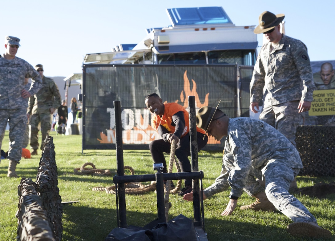 Ray Duffy, a massage therapist student from Oceanside, Calif., challenges himself at the Army Reserve challenge flanked by drill sergeants from 2nd Battalion, 413th Regiment, 95th Training Division at the 2015 Southern California Tough Mudder race in Temecula Oct. 31. The U.S. Army Reserve was a sponsor of the Tough Mudder this year, which meant Reserve Soldiers spotted, motivated and assisted racers at the obstacles. Duffy said he wanted to try the challenge (pushing a weighted sled, five pullups, low crawl, 20 pushups, and pulling the weighted sled back into place), because it looked like fun, and he’s a supporter of the U.S. Army. (Photo by Sgt. 1st Class Alexandra Hays, 201st Press Camp Headquarters)