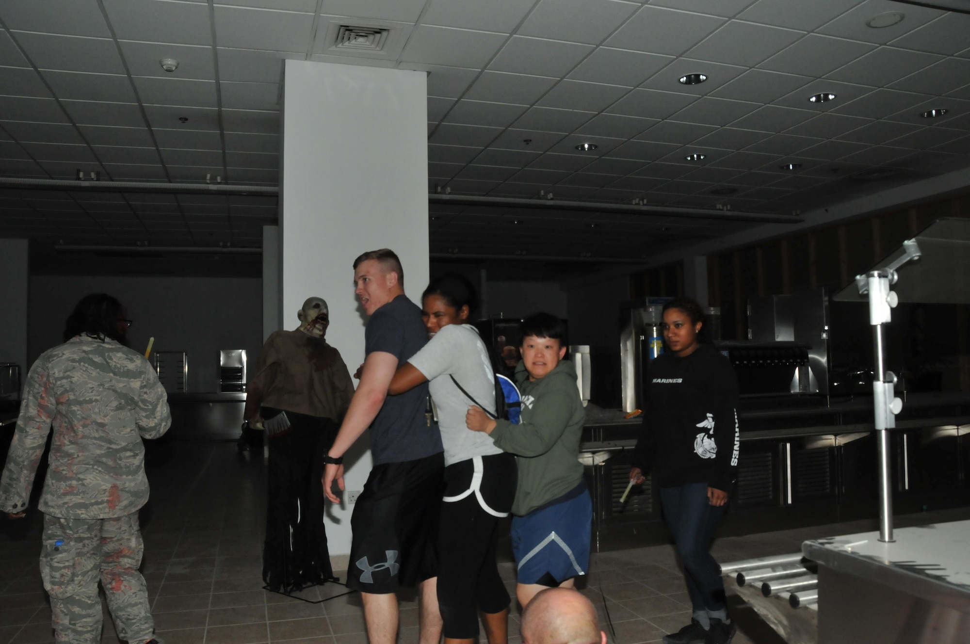 Service members stiffly maneuver through the haunted house hosted by the 379th Expeditionary Logistic Readiness Squadron at Al Udeid Air Base, Qatar Oct. 30. As zombies grab at participants’ feet in the dark, screams could be heard from the service members. (U.S. Air Force photo by Tech. Sgt. Terrica Y. Jones/Released)