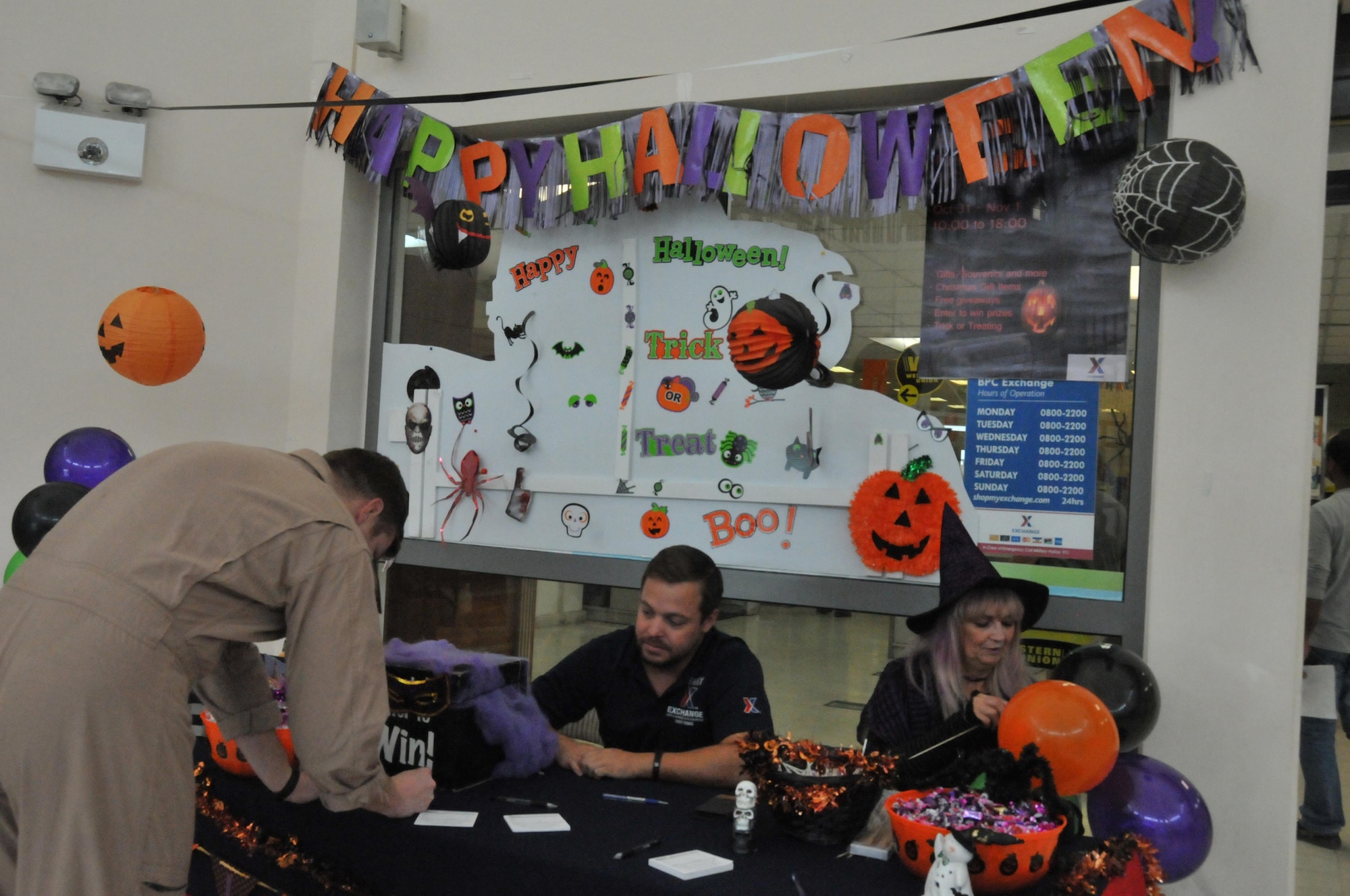 Happy Halloween greets service members as they fill out drawing slips for a chance to win a prize at Al Udeid Air Base, Qatar Oct. 31. The Base Exchange offered a variety of prizes including a grand prize of either a TV or a game console. Base Exchange employees manning the table offer candy to people as they visit the BX. (U.S. Air Force photo by Tech. Sgt. Terrica Y. Jones/Released)