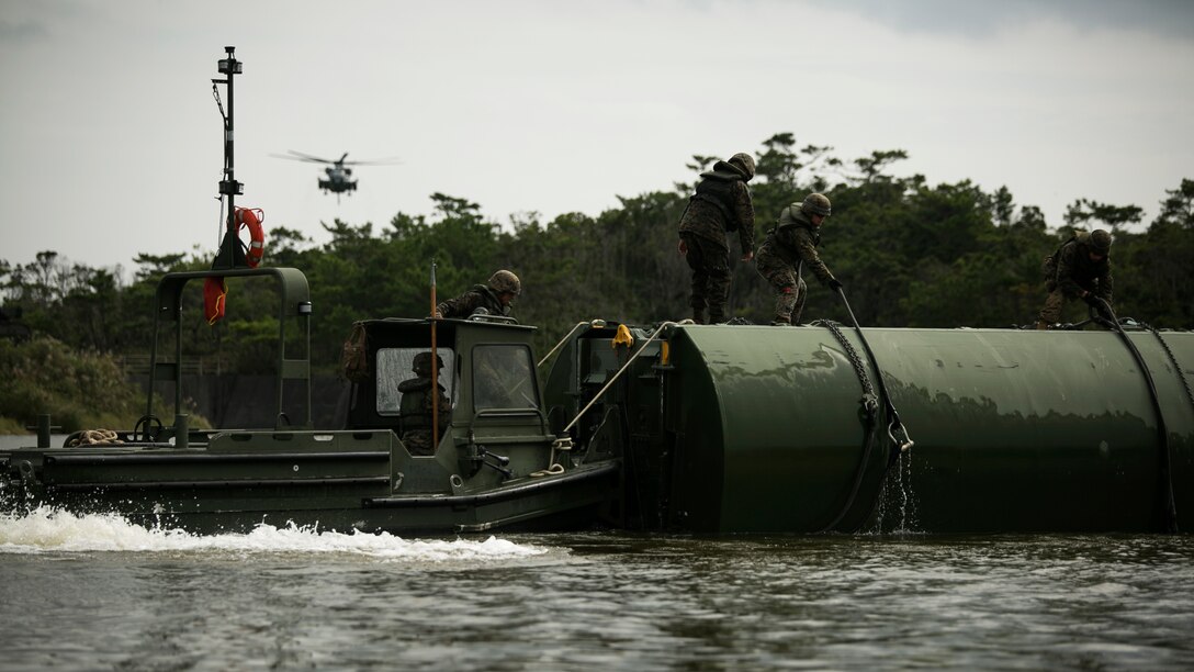 Marines move a component of a 15-bay Improved Ribbon Bridge as a CH-53E Super Stallion helicopter descends to airlift more bridge components into the water in the Central Training Area, Okinawa, Japan, during Blue Chromite 2016, Nov. 2, 2015. This was the first time that Improved Ribbon Bridges, flat modular-floating platforms that bridge wet gaps, were inserted by air on Okinawa. Blue Chromite is a large-scale amphibious exercise that draws primarily from III Marine Expeditionary Force’s training resources on Okinawa. The location of the training allows participating units to maintain a forward-deployed posture and eliminates the cost of traveling to train. The Marines are with 9th Engineer Support Battalion, 3rd Marine Logistics Group, III Marine Expeditionary Force. The Super Stallion is with Marine Heavy Helicopter Squadron 462. (U.S. Marine Corps photo by Cpl. Drew Tech/Released)