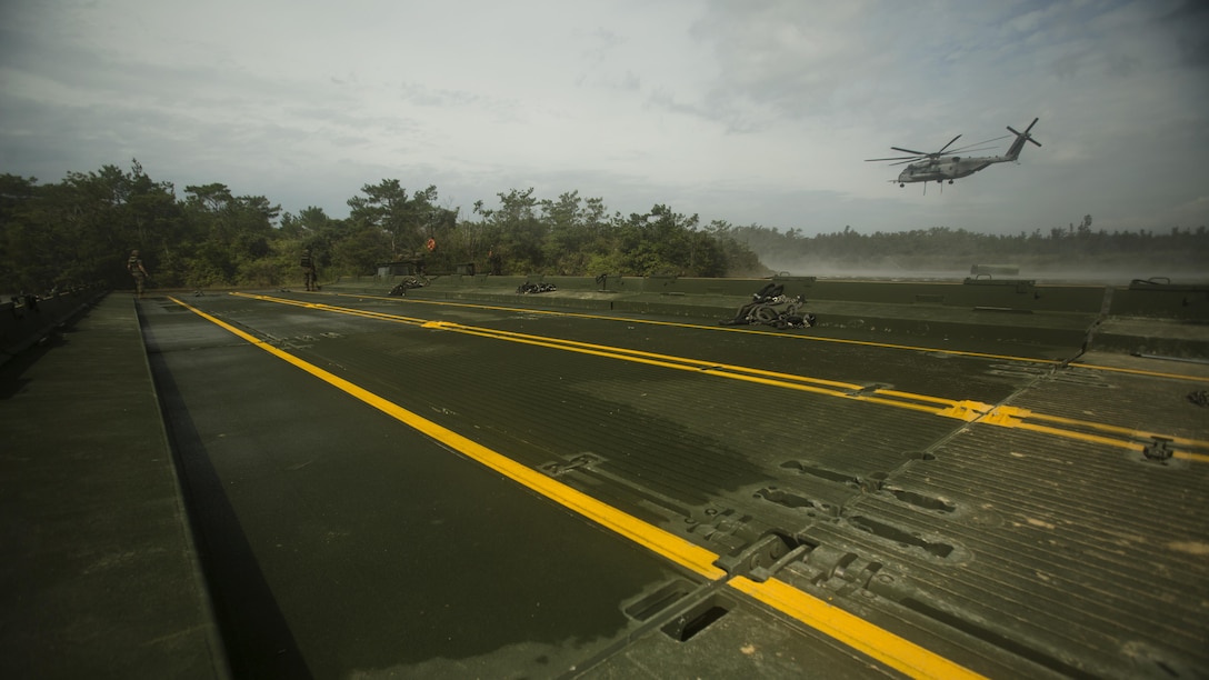 Marines work to complete a 15-bay Improved Ribbon Bridge as a CH-53E Super Stallion helicopter inserts bridge components into the water in the Central Training Area, Okinawa, Japan, during Blue Chromite 2016, Nov. 2, 2015. This was the first time that Improved Ribbon Bridges, flat modular-floating platforms that bridge wet gaps, were inserted by air on Okinawa. Blue Chromite is a large-scale amphibious exercise that draws primarily from III Marine Expeditionary Force’s training resources on Okinawa. The location of the training allows participating units to maintain a forward-deployed posture and eliminates the cost of traveling to train. The Marines are with 9th Engineer Support Battalion, 3rd Marine Logistics Group, III Marine Expeditionary Force. The Super Stallion is with Marine Heavy Helicopter Squadron 462. (U.S. Marine Corps photo by Cpl. Thor Larson/Released)