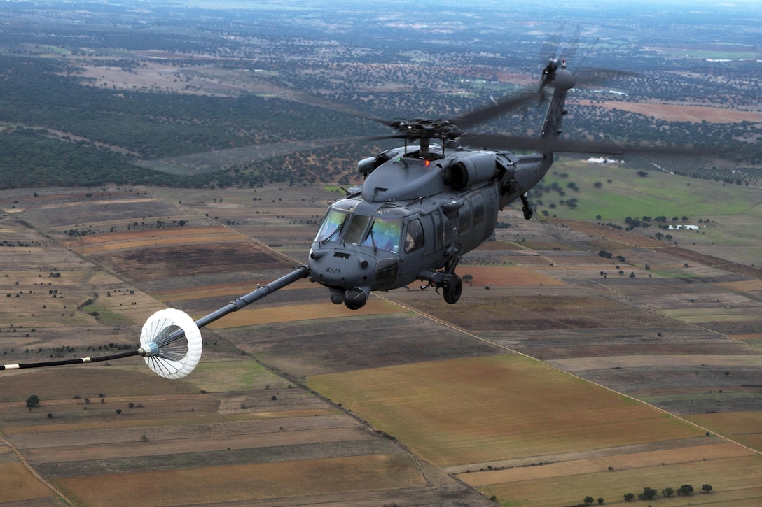 An HH-60G Pave Hawk helicopter refuels through a drogue from a C-130J Hercules aircraft during the air refueling training part of Trident Juncture near Beja Air Base, Portugal, Oct. 23, 2015. The helicopter pilots are assigned to the 41st Rescue Squadron. U.S. Air Force photo by Airman 1st Class Luke Kitterman