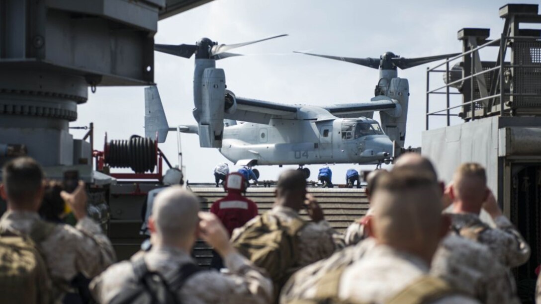 Sailors and Marines look on while a MV-22 Osprey aircraft lands on the flight deck aboard the amphibious dock landing ship USS Germantown (LSD 42) during exercise Blue Chromite 16 in Okinwa, Japan, Oct. 28, 2015. BC 16 is a U.S. only exercise designed to increase amphibious proficiency between the Navy and Marine Corps.