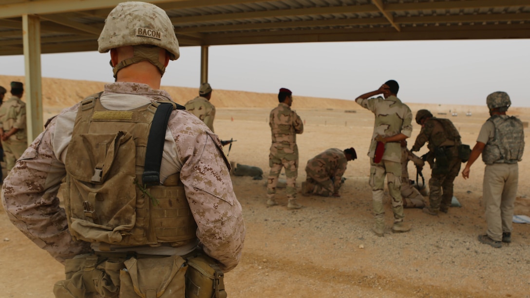U.S. Marine Cpl. Kyle Bacon, left, a team leader with Weapons Company, 1st Battalion, 7th Marine Regiment, provides security for Royal Danish Army shooting instructors during a live-fire range at Al Asad Air Base, Iraq, Oct. 26. The training was conducted as a part of the building partner capacity mission utilizing both U.S. and Danish forces to teach the Iraqi security forces proper weapons handling and other various combat skill sets. 